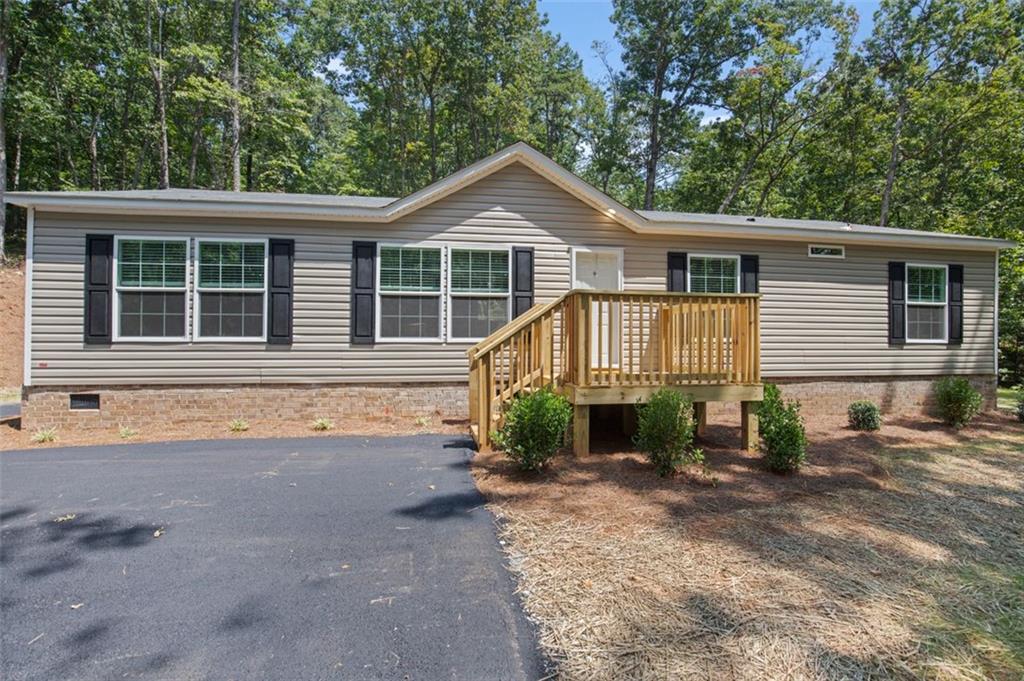 Welcome home! Ranch-style Home in a neighborhood with beautiful North Georgia Mountain Views. Looking to find the perfect affordable home in the North Georgia mountains? It's time to take a closer look at a quality manufactured option. This charming 4 bedroom, 2.5 bath in Clarkesville offers modern comfort, breathtaking scenery, and a peaceful, private setting - all at an unbeatable under $300k price point.
It boasts a spacious, open floor plan perfect for entertaining with a large kitchen island and breakfast bar, as well as beautifully finished drywall, tile backsplashes, and a high pitched roof. This home sits on a permanent poured concrete foundation with real brick surround. Using the latest engineering techniques, this home offers all the longevity and safety of a traditionally built home at an accessible price point. The well appointed owner's suite is large and features dual vanities, a walk-in shower, and linen storage. The living area is open concept and includes an electric fireplace and room in the dining room for friends and family to gather. Enjoy the mountains on your own .8 acres of property with mature hardwoods, and plenty of space to expand. The lot has a very private feel with an asphalt driveway and three parking spaces.
Clarkesville is a prime location in Northern Habersham. Just far enough out to maintain a small town atmosphere while still being close to a healthy, active community, great schools, and quality health care. This home is eligible for USDA 100% loans, FHA, VA, and conventional financing. Whether you're just starting out or ready to retire with financial peace of mind, this home is a great place to put down roots. Everything in this home is brand new and under warranty, ensuring your peace of mind. Don't miss this opportunity! Preferred lender program with lender credits and special financing available. Schedule your showing today. SELLER HAS A REAL ESTATE LICENSE. AGENT OWNED.
