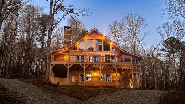 Property with a chimney, a wooden deck, and log veneer siding
