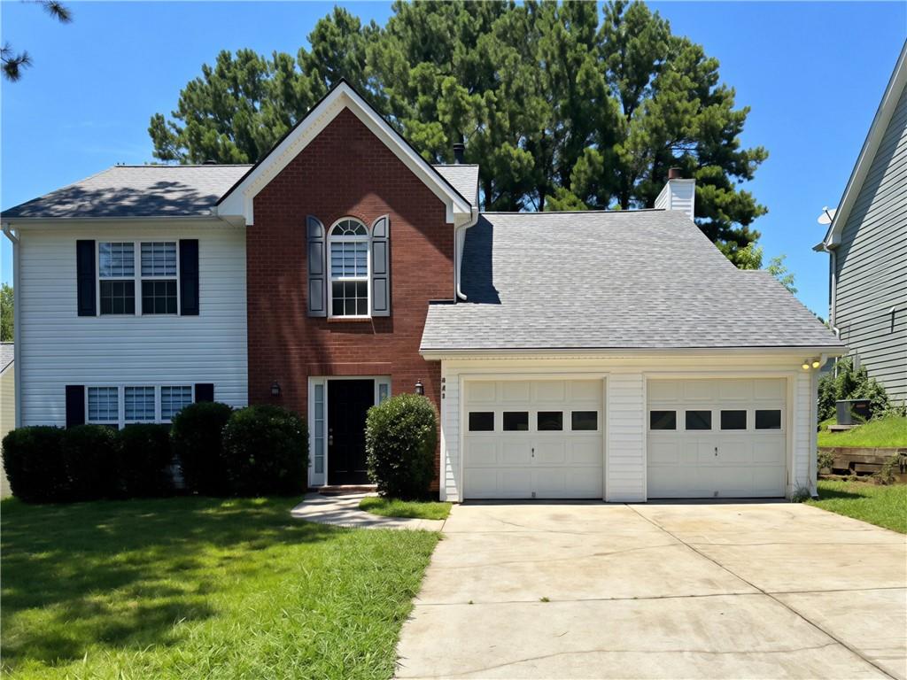 Two-story residence featuring brick and siding facade, a two-car garage, and an arched window above the main entry