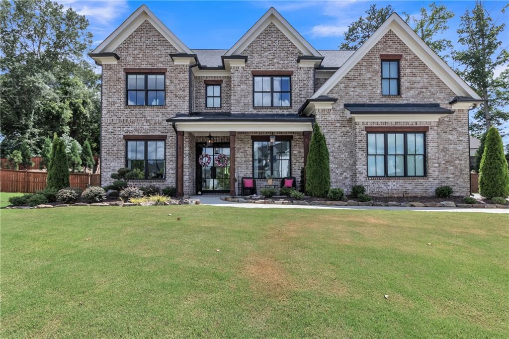 Experience timeless elegance and modern luxury in this stunning 5-bedroom, 4-bath home built in 2021, ideally situated on a spacious lot in Buford’s most desirable community. From the moment you step inside, you’ll be captivated by the refined entry, soaring ceilings, extensive trim work, and upscale finishes throughout. The open-concept layout features a show-stopping chef’s kitchen with quartz countertops, oversized island, stainless steel appliances, custom lighting, and designer cabinetry—flowing seamlessly into the coffered-ceiling living area with stone fireplace and panoramic views of the private backyard oasis. A stylish formal dining room with paneled walls and statement chandelier provides the perfect setting for entertaining. The main-level guest suite and a sleek full bath with floor-to-ceiling marble tile offer both function and elegance. Upstairs, discover a luxurious owner’s suite with a dramatic accent wall, spa-like bath, and generous closet space, along with secondary bedrooms, a loft/media room with custom shelving, and a convenient laundry closet with built-in cabinetry. Outdoors, unwind in the resort-style yard complete with a sparkling pool, lounging area, and professionally landscaped grounds. Located in a premier community with clubhouse, pool, playground, sidewalks, and proximity to top-rated schools and shopping—this home is the perfect blend of comfort, style, and lifestyle convenience.