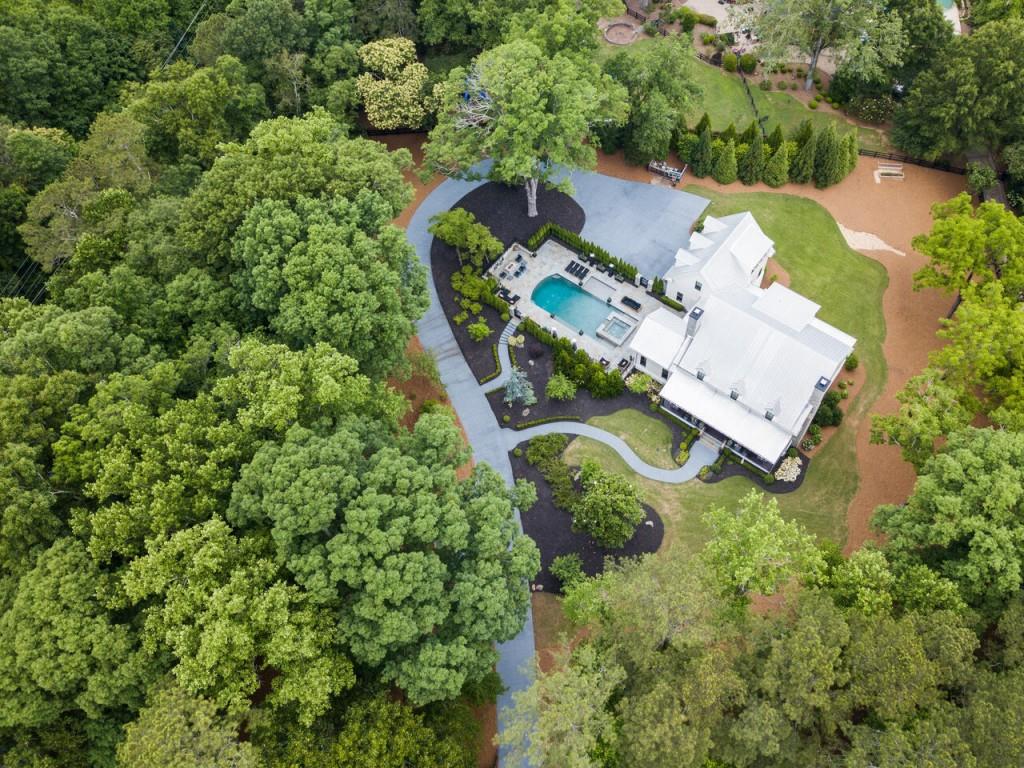 Gated modern custom farmhouse built by Steve Powell Homes. Located minutes from downtown Alpharetta, Avalon and highway GA 400. Home is overlooking 100 year old whispering oak trees and sits beautifully on 2.45 +/-acres. Large front porch with cedar beams featuring tongue and groove ceiling, two porch swings. Walk out from your first floor through Lanai Bi-folding glass doors that lead to an amazing heated pool, with spa and accent waterfall. Full pool Bath and Fire Pit makes entertaining outdoors effortless. 12 foot ceilings on Main Level, Open Floor plan invites you into the Chefs kitchen with rustic beams ceiling, high-end appliance package, large island with farm sink, quartzite countertops, and custom built vent hood. Pennsylvania Barn wood Hardwood flooring throughout. Beautiful windows on the main floor bring in loads of natural light. Exquisite design selections throughout the home including tile, light fixtures, and hardware. Owners suite on Main Level with spa like bath with heated floors, large his and hers closet with island, custom built-ins. Wonderful laundry/mud room with two washers and two dryers, sink and tons of storage. Large secondary bedrooms upstairs with private baths and great walk-in closets featuring custom built-ins. Cozy study nook. Terrace Level features; bedroom with full bath, workout room, home theater, boat/car garage/workshop with great storage space with built-ins. Beautiful winding driveway with additional parking pads for entertaining, generator, Control 4 Home automation that controls lighting, HVAC and security system.