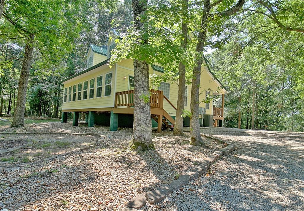 Discover your dream home nestled on 3.56 acres of serene countryside in Hampton, GA. This charming residence features 3 bedrooms, 2 full baths. Step inside to be greeted by hardwood floors that flow through the family room, showcasing a stunning floor-to-ceiling stone pellet wood-burning fireplace and a vaulted ceiling that extends to the second floor. The open floor plan seamlessly connects the family room to the kitchen, perfect for both everyday living and entertaining. A versatile pantry with trifold doors can double as a laundry room if preferred. The master suite on the main floor boasts hardwood flooring, a master bathroom with a soaking tub, and a separate shower. Upstairs, you'll find two additional bedrooms and a full bathroom with double sinks, providing ample space. Enjoy your morning coffee in the sunroom or unwind on the covered back deck, both offering picturesque wooded views. The expansive detached 3-car garage includes a full bathroom and workshop with an A/C window unit, ideal for hobbyists or additional storage. The property is adorned with apple and pear tree, adding a touch of orchard charm. All 3.56 acres are fenced in, providing privacy and security. A sprinkler system is installed in both the front and back yards, ensuring lush landscaping year-round. Plenty of room in the back yard for a pool. The home features a durable tin roof, adding to its rustic appeal. Don't miss the opportunity to make this enchanting Hampton home your own. Schedule a viewing today!