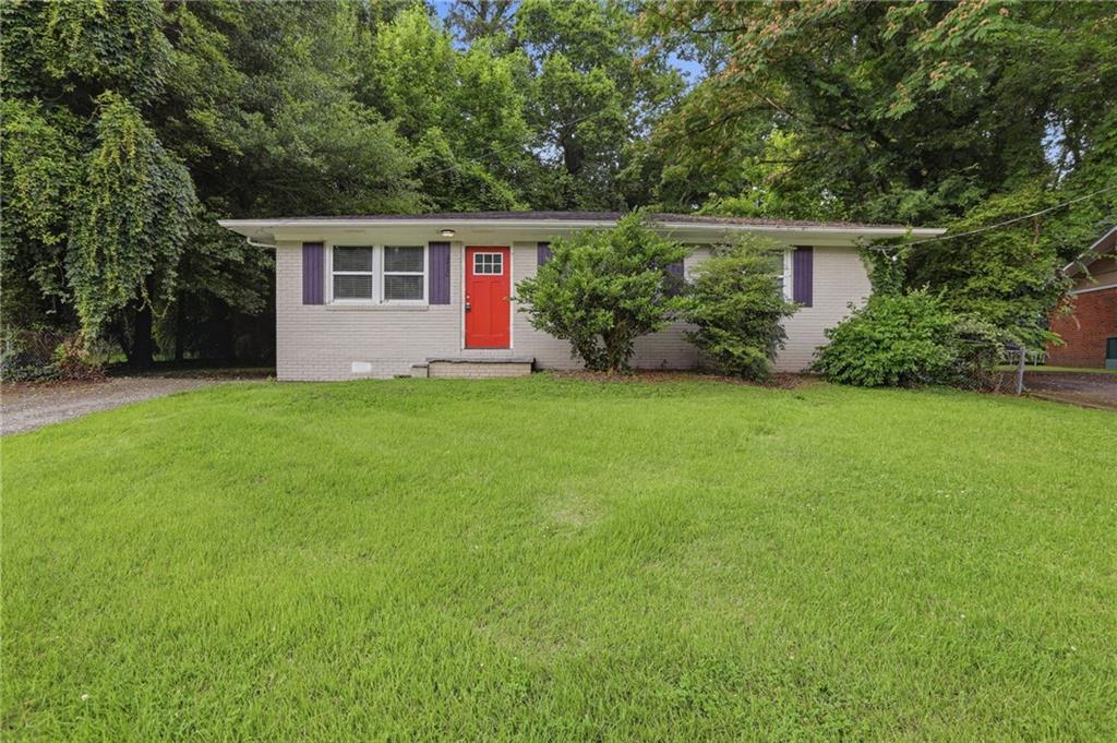 Single-story residence featuring a light gray brick exterior, a vibrant red entry door with grid detailing, and purple decorative shutters