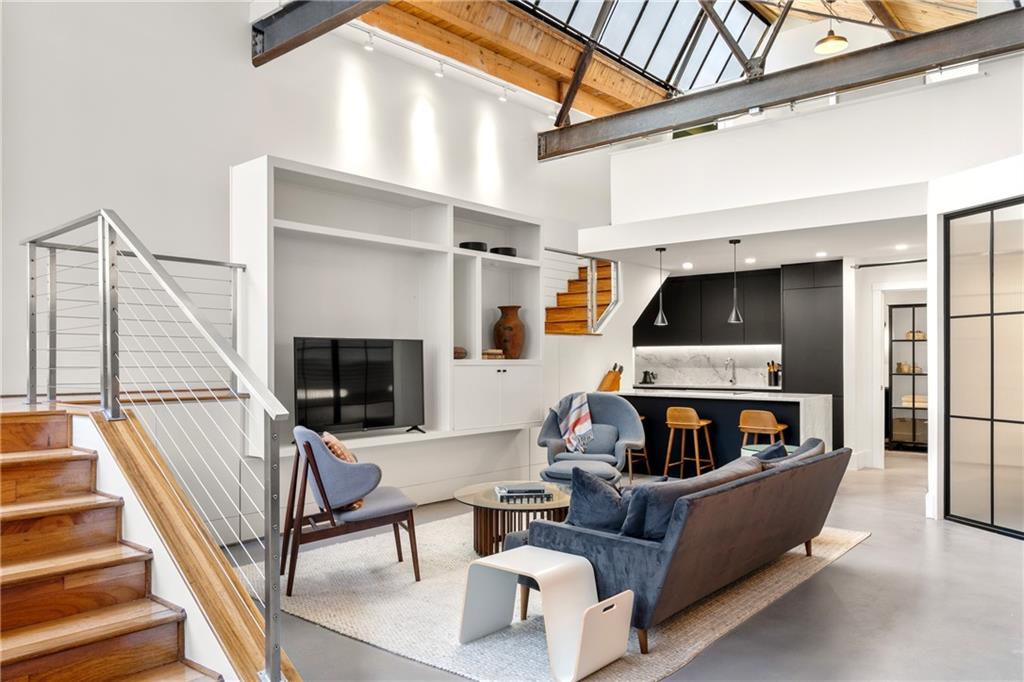 An Atlanta landmark reimagined—Residence #7 at Troy Peerless Lofts pairs dramatic sawtooth ceilings, exposed steel beams, and original exposed brick with modern bespoke designer finishes. Literally across the street from Ponce City Market and the BeltLine, this residence offers rare conveniences including two side-by-side parking spaces across from the home’s front door, two secure private storage units, and generous hidden storage in the home—an unmatched amenity package for intown loft living.
Spanning approximately 1,890 square feet, this home is the pinnacle of living in the historic Troy Peerless Laundry building, constructed in 1929 and now listed on the National Register of Historic Places. Architectural authenticity is preserved with soaring cypress ceilings, dramatic clerestory windows, and factory-scale steel-framed windows that flood the interiors with natural light. Original brick walls meet refinished concrete floors, while a sculptural chandelier and exposed steel beams emphasize the loft’s industrial drama.
The designer kitchen is a study in refined detail with Bianco Supiore quartzite waterfall countertops, custom flat-paneled cabinetry, concealed Gaggenau, Miele, and Bosch appliances and modern pendant lighting over an expansive peninsula.
The Primary main-level bedroom retreat is enclosed with Rustica steel + glass dividers, balancing lofty openness with privacy. An industrial chic bath showcases seamless microcement finishes, a floating vanity topped in quartzite, Kohler fixtures, and a steel + glass shelving system.
Troy Peerless Lofts offers boutique amenities including a rooftop terrace with skyline views, fitness center, clubhouse, landscaped courtyard, and pet-friendly spaces with secure gated access.
Investor-friendly and turn-key, Loft #7 has a proven rental history, and the building has extremely flexible rental rules. The high-end designer furnishings are available for purchase if you so desire, offering buyers the option of a complete, ready-to-go lifestyle or income property.
Integrated smart home automation provides effortless control of lighting, audio, and climate, and a new HVAC system ensures modern comfort.
Anchored in the heart of Old Fourth Ward, this loft places the BeltLine, Old Fourth Ward Park, and the city’s best dining, shopping, and cultural experiences just beyond your door.
650 Glen Iris Drive #7 is timeless loft architecture elevated with modern design—an extraordinary opportunity where history, luxury, and
investment potential converge.
