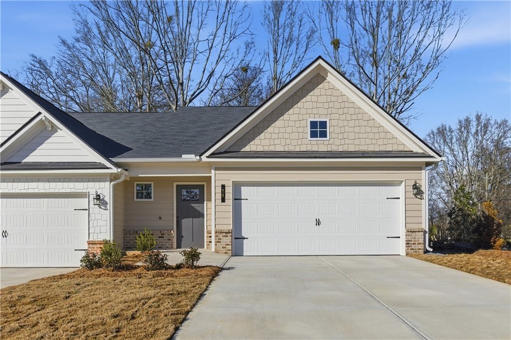 Craftsman house featuring a porch, brick siding, driveway, and an attached garage