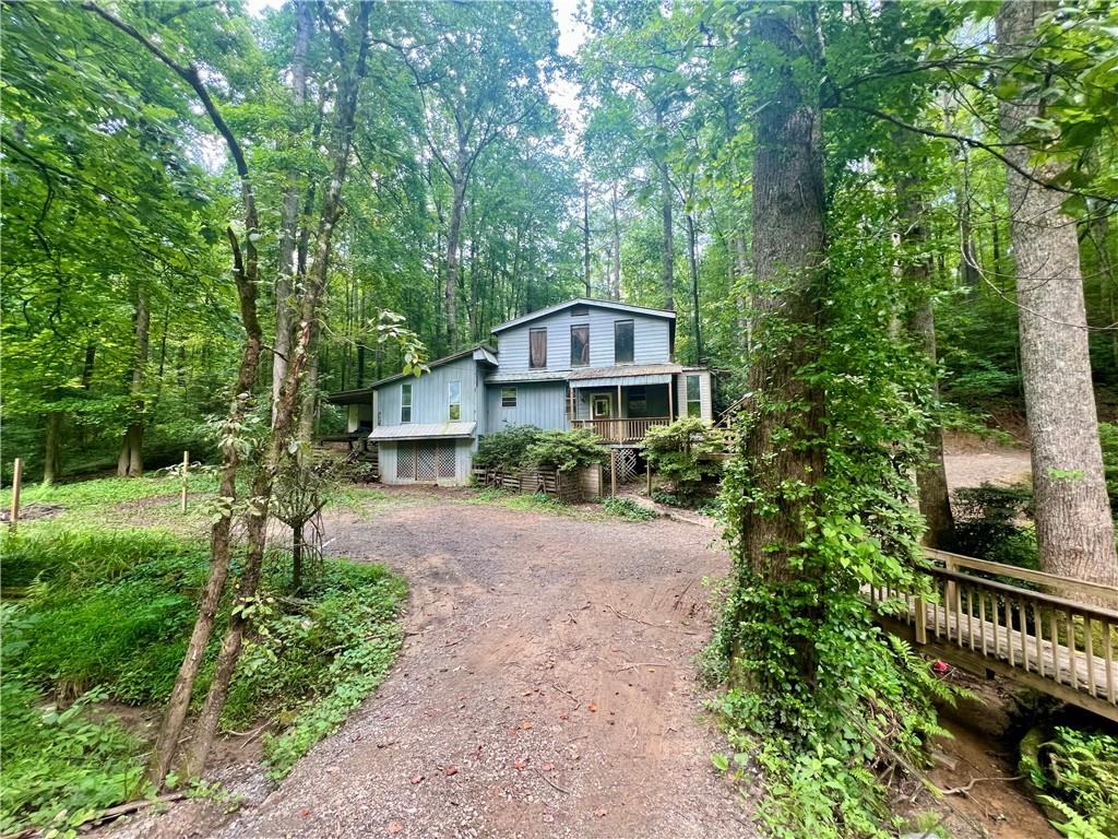 Wooded property featuring a two-story residence with light blue siding and multiple windows