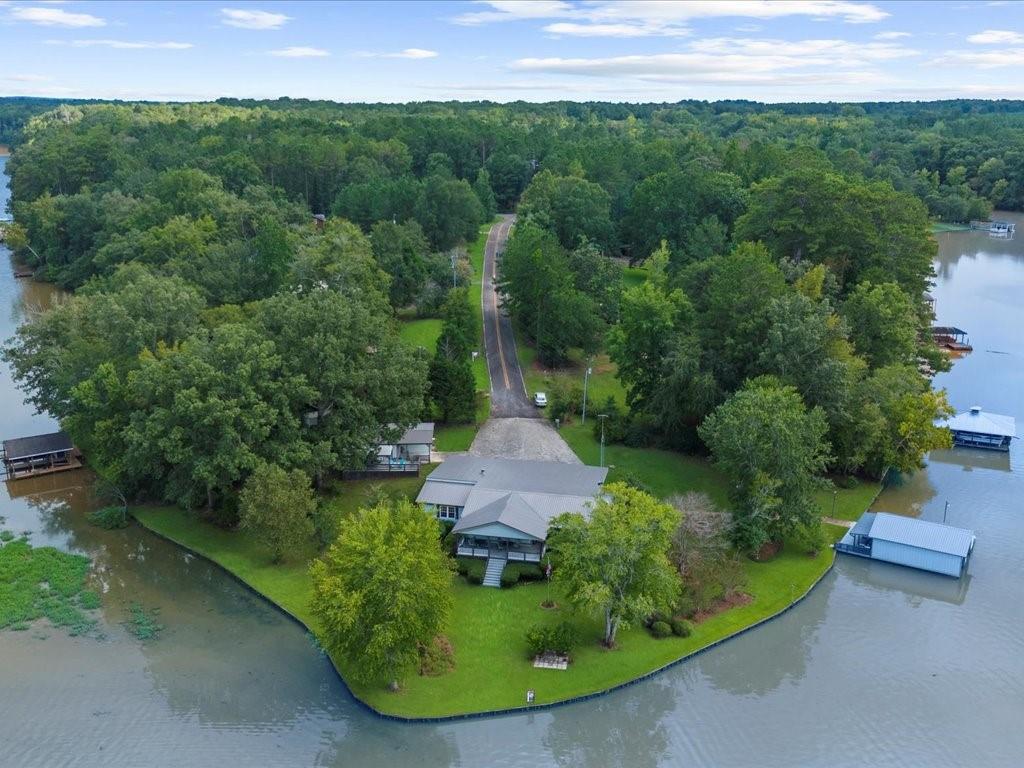 Lake Sinclair Private Oasis: Two homes, enclosed dock, 450+ feet of shoreline, seawall, and a premier lakefront lifestyle on rare deeded fee simple lot. This multigenerational retreat offers the rare combination of space, privacy, and natural beauty with two residences on a protected, deep-water shoreline.
The main home features three bedrooms and two full baths, all designed to take in lake views from every room. A massive wraparound deck with a covered area provides year-round outdoor living and entertaining space, while the level yard invites outdoor activities and gatherings. The enclosed dock area includes two slips, a covered boat lift, and a storage room for tackle, floats, and other water-sport essentials, all protected by a sturdy seawall along more than 450 feet of shoreline.
The second residence is a charming cottage offering one bedroom and one bath, a comfortable living room, a kitchenette, and a covered deck that overlooks the tranquil waters—perfect for guests, in-laws, or rental income.
A well-appointed workshop adds practical value, featuring an upgraded water filtration system for dependable, clean water throughout the property. The property sits in a premier fishing area and is ideal for nature lovers, anglers, and anyone seeking a serene, lakefront lifestyle.
This property presents a unique opportunity to combine privacy, investment potential, and the unparalleled appeal of Lake Sinclair. Schedule your private tour to experience the lifestyle this two-home oasis has to offer.