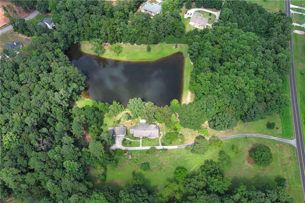 Desirable estate at 3102 Walt Stephens Road! This stunning 3-bedroom, 2.5-bath home is nestled on a sprawling 10.691-acre property that includes a private 2.5-acre stocked lake, offering 2,996 square feet of living space. Perfectly designed for both comfort and entertainment, this property is truly a hidden gem. This property has combined separate parcels to create 10.691 acres. Clayton Co. has approved and registered the plat in June 2025 (Plat book 46/ Page 57). Step inside to discover a beautifully updated kitchen featuring custom cabinets and elegant quartz countertops, making it ideal for culinary enthusiasts. The kitchen seamlessly opens into the living room, anchored by a large fireplace, and is adjacent to an oversized den or dining area, which also features a second cozy fireplace. Across the back of the two main living areas, a beautiful sunroom with a wood-burning stove that overlooks the patio and private lake, providing breathtaking views of the water, wildlife, and sunrises. The home features a split bedroom layout, with an oversized master suite that includes three walk-in closets and a lavish ensuite bathroom equipped with two separate sink counters, a soaking tub, and a spacious shower. Two additional large bedrooms, one of which has a fireplace that could also serve as an office or den, share a generous guest bathroom. Off the kitchen, you'll find the laundry room and a half bath. Two additional rooms in the main house are currently used as a storage/craft room and a mudroom, which house a backup freezer and refrigerator, as well as an in-house vacuum system. This house offers plenty of storage options. Outside, the property is adorned with mature dogwoods, gardenias, azaleas, hydrangeas, crape myrtles, irises, lilies, and fig trees, ensuring something is blooming year-round. There are charming plots to create your farm-to-table garden and cozy sitting areas perfect for hosting gatherings with family and friends. Enjoy swimming, fishing, or paddling around on your private lake, or simply relax on the patio or dock with your morning coffee. Separate from the house, you will find a freestanding workshop/garage and a covered area with a cement floor that can serve as a patio or a two-car carport, along with a covered space for outdoor storage. This property truly has it all. Don't miss your chance to experience the perfect blend of luxury, comfort, and outdoor living at 3102 Walt Stephens Road, conveniently located 5 minutes from I-75, a 20-minute commute to Hartsfield-Jackson International Airport, and downtown Atlanta is only a 30-minute drive. Schedule your private showing today!