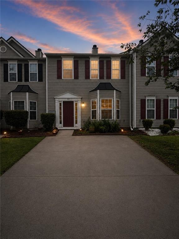 Traditional-style townhouse exterior featuring horizontal siding and dark red window shutters