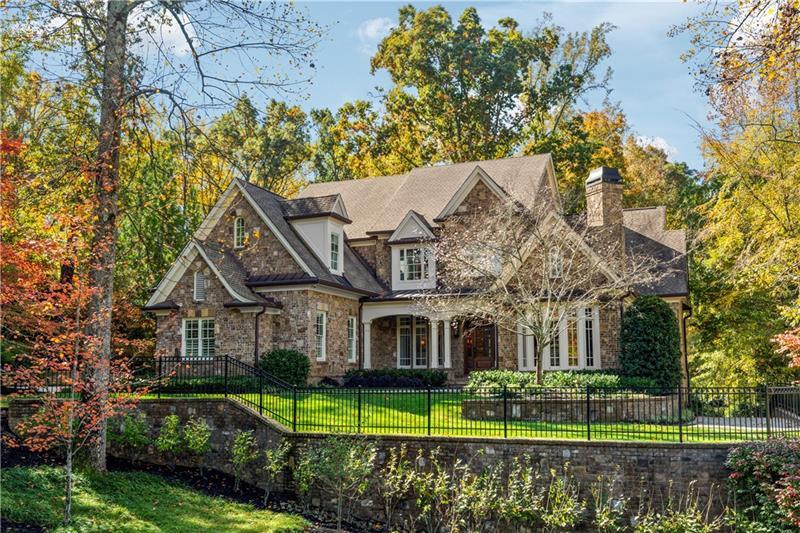 A stunning brick and stone exterior sets a tone of subtle sophistication found throughout this English country style residence on over an acre of private land. Interior details curated to accentuate the home's understated elegance include handcrafted random length and width dark oak flooring, custom beveled glass antique doors, exquisitely detailed millwork and custom lighting. The well-appointed, traditional floor plan includes an inviting entrance foyer with herringbone patterned hardwood floor detail, formal living room, oversized dining room and richly paneled den. Open to a light filled eat-in breakfast area and vaulted family room with antique wood beams and a stacked stone wood burning fireplace, the show-stopping kitchen features premium appliances, custom cabinetry, a walk-in pantry, large center island with prep sink, 2 dishwashers and separate Butler's pantry. The main level primary suite offers a welcome retreat with an indulgent bath featuring heated marble floors, a walk-in shower, soaking tub, dual sinks and closets and access to a private screened porch. Four en-suite bedrooms occupy the spacious upper level along with an abundance of storage. Open to a private tree-lined backyard, the daylight terrace level offers additional living space with an entertainment room, a hand-crafted 1,000 bottle capacity commercially air-conditioned wine cellar, private guest suite, and access to a covered brick patio with gas grill and adjacent fieldstone patio. Yard is "pool ready" if one desires. A state-of-the-art Control4 home automation system controls the lighting, entertainment system, HVAC and home security though a mobile app and a series of touchscreens throughout the home. Newly installed custom garage doors feature MyQ mobile control and camera monitoring are in place for the main level 3-car garage and additional 4-car garage accessible by a hidden driveway system. Ideal location minutes to top area private schools, Chastain Park, I-285, shopping and restaurants.