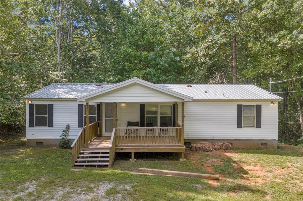 Nestled in the foothills of the North Georgia mountains, this well-kept 3 bedroom, 2 bath manufactured home rests on 1.1 acres with a permanent foundation in northern Dawson County and is being offered for the first time by the original family. The home welcomes you with a large covered front porch, the perfect spot for morning coffee or unwinding in the evening. Inside, you’ll appreciate the desirable open-concept design with a split-bedroom layout and a versatile bonus room that could serve as an office, dining room, playroom, rec room, or den. The spacious eat-in kitchen includes pantry storage and offers the option to add a center island or coffee bar for extra workspace and seating. The master suite features a double vanity, tiled shower/tub combo, walk-in closet, and tile flooring. Most of the interior has fresh paint, with laminate flooring throughout and tile in the bathrooms. The exterior is low-maintenance with vinyl siding and a durable metal roof. The home has central heat and air, along with a propane wall heater for backup. The land extends to the top of the hill behind the home, giving you plenty of space to fence in, ride ATVs, or explore. For outdoor enthusiasts, the location couldn’t be better—just 15 minutes from Amicalola Falls State Park, the Amicalola River for trout fishing, tubing, and kayaking, Dawson Forest WMA for hunting, and Jakes/Bull Mountain for biking and horseback riding. Titles have already been retired, this home could be your perfect mountain retreat or full-time residence.