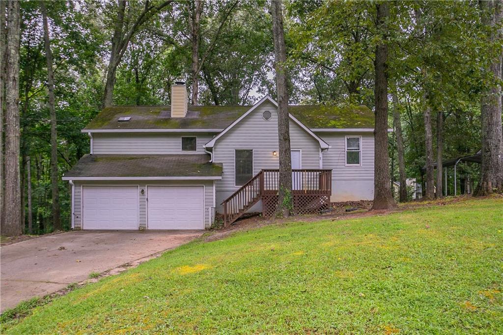 Welcome to this versatile 4-bedroom, 2-bath split-level home nestled on a spacious wooded lot in Evans Forest Estates. The main level features a large great room with hardwood floors and a beautiful stone fireplace, flowing into a separate dining area ideal for gatherings. The split-bedroom layout offers privacy, with the oversized primary suite on one side and two secondary bedrooms on the other. Downstairs, the finished basement includes a fourth bedroom, a media or game room, laundry area, and a kitchenette—perfect for guests, extended family, or a private office. The attached two-car garage also includes a large workshop area for storage or creative use. Enjoy peaceful mornings on the front porch or unwind in the expansive, tree-lined backyard.
