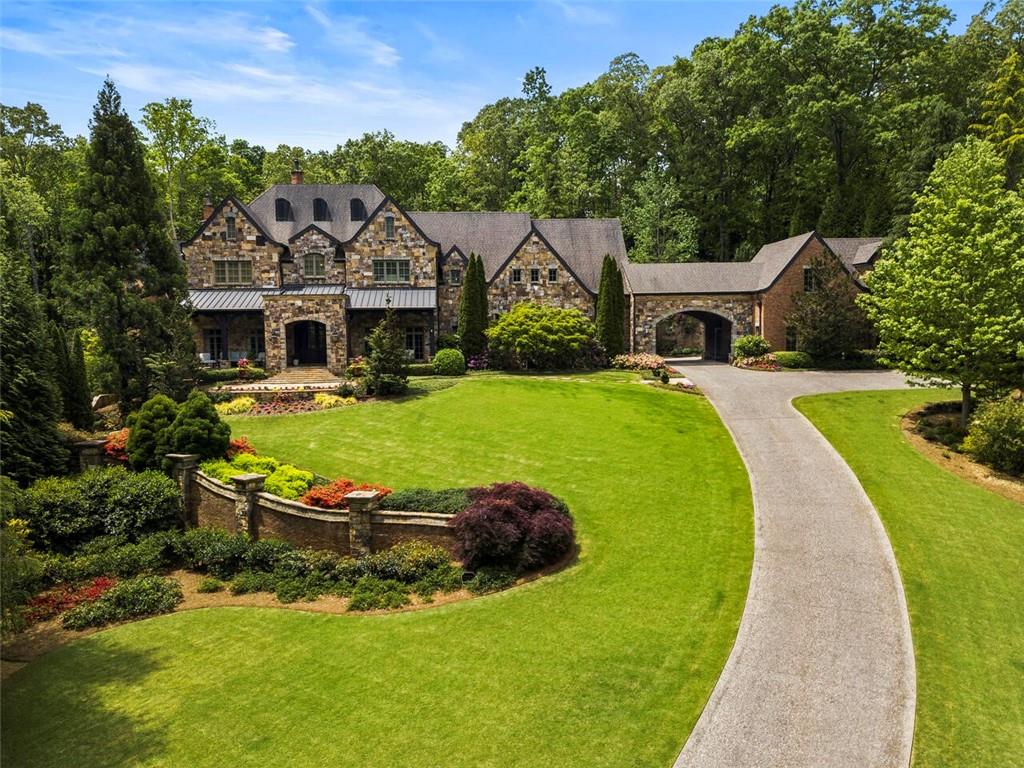 Every inch of this impressive Harrison Design custom home has been meticulously curated using the highest-quality materials, craftsmanship, and design aesthetic. The finely crafted interior resonates with classic and enduring details including intricate millwork, arched doorways, plaster walls, exposed wood beams and soaring ceiling heights. Open to the dramatic vaulted keeping room, the show-stopping kitchen features a mix of natural stone and wood elements, top-of-the-line appliances and custom cabinetry providing a stunning backdrop for entertaining on a grand scale. The fireside main level primary suite offers a relaxing morning bar, sitting area, two walk-in closets and sumptuous bath complete with dual vanities, walk-in shower and a separate soaking tub. Well-appointed terrace level includes every amenity expected in a home of this caliber including a private guest suite, mini kitchen, wine cellar, billiards room, exercise room, workshop and safe room. The meticulously designed grounds create a welcome oasis anchored by an expansive stone sun patio, saltwater pool with cascading waterfalls, pool house, summer kitchen and fireside porch with automatic screens. Additional enviable features include all en-suite bedrooms, a 5-car garage with guest suite above, Sonos and Control4 systems, and elevator access to all levels. Highly sought-after East Cobb location with award winning schools and low taxes!