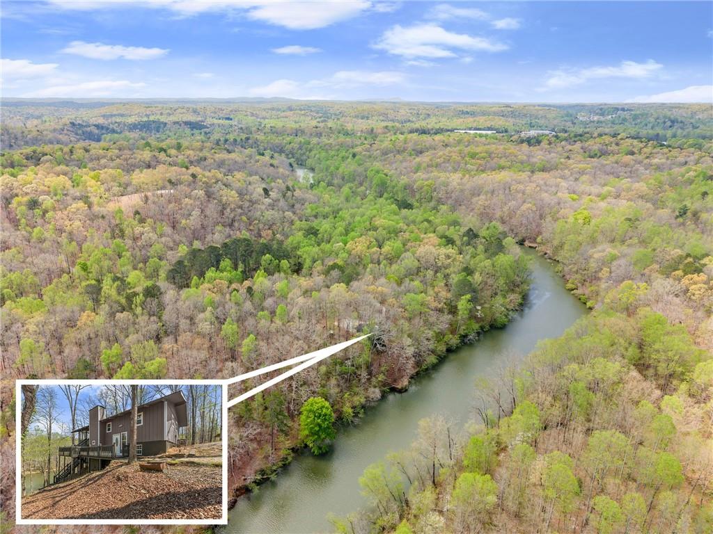 A Rare Riverfront Retreat…Chestatee Riverfront Home | Dahlonega, GA Discover one of North GA’s most unique & private properties.
An extraordinary .32-acre riverfront lot tucked among 1,000s of acres of protected U.S. Army COE land with stunning Chestatee River frontage. Just a short drive to North Atlanta, yet a world away in privacy & natural beauty. This 4 Bedroom/2 Bathroom cabin style home is perched in the big woods overlooking the river. Updates include new kitchen w/ stainless steel appliances, quartz counters, LVP floors, & tiled bathrooms. Open concept living room features a full masonry fireplace & flows to a sprawling screened porch w/ sweeping river views. Main level offers 2 Bedroom/1 Bath; terrace level has 2 more bedrooms, 2nd living area w/ front porch, & large open air porch. Private shared drive adds seclusion, & you can boat to your property from Lake Lanier. Park with boat launch nearby. Enjoy easy access to essentials..new NE GA Medical Center on GA 400 mins away, plus new Tractor Supply, Publix, & Home Depot just around the corner. Charming Dahlonega, named one of the South’s best small towns by Southern Living, is nearby offering a historic square, award winning wineries, & vibrant culture. Perfect as a weekend retreat, full time residence, or rare investment. Experience life on the river!