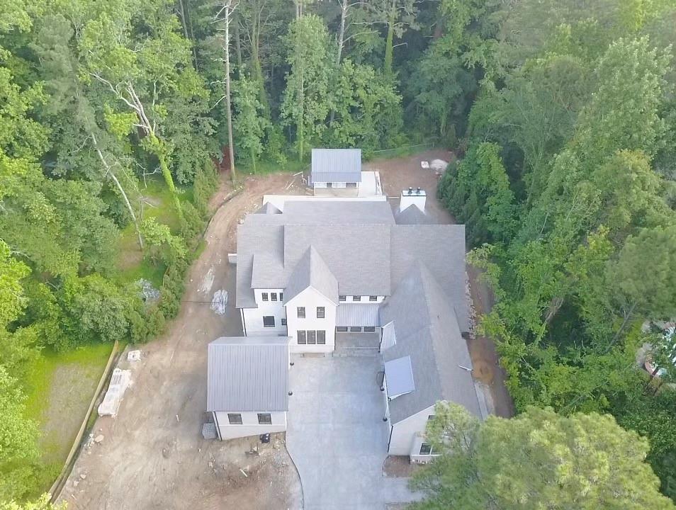 This Modern Farmhouse in the Chastain Park area, is on 1.6 private acres. The securely gated, long, private driveway opens to your beautiful home in the woods, with convenient in-town living. Once inside, the 12’ ceilings, custom iron window-walls-doors, and simple design create a light-filled space that pulls you in, and makes you want to stay. Pool, pool house, outdoor kitchen, wet bar, prep areas, and more make this home an absolutely perfect place for entertaining and luxury living. The gourmet kitchen features extravagances, a LaCornue Chateau Series Range/Oven, in many celebrity homes. Center island w/ quartz waterfall countertop for casual seating leads to the open dining area. A butler’s pantry for extra prep, and a vast walk-in pantry. A separate bar area w/ ice, wine tower, and beverage fridge. There is a separate apartment off the main floor, with kitchen and bath. 
Open great room w/ beams, a stone fireplace as its centerpiece, plenty of light and window-wall doors that walk out to the gorgeous outdoor living, and a separate screened-in porch. Master on main with his/her closets, a private laundry, and luxury master bath. Many office options available with dedicated wiring. An office/bedroom on the main has a full bath and closet. Upstairs has 3 spacious bedrooms with private baths, and a common area, leading to a covered balcony. Large upstairs laundry. Permanent stairs to the attic.
Pebble-Tech salt water pool, which includes a pool house w/ apartment, full bath and kitchen, covered outdoor kitchen with gas grill.
4-car garage, golf-cart garage. Mudroom. Plenty of yard space for playsets. 
Finished Terrace level with bedroom and bath.