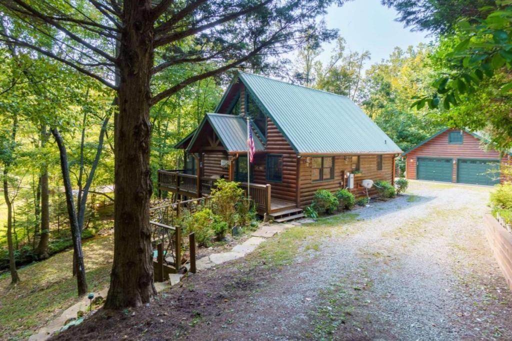 Discover this beautifully maintained 3BR+ 1 room used as a 4th & 3BA log home just 10 minutes from downtown Blue Ridge. Nestled on 1.55 acres with 385 feet of rushing creek frontage (Mitchell Branch), this property is a rare find. Features include a screened porch overlooking the creek and adjoining pond, a 2-car detached garage, and a new outdoor pavilion & stone fireplace. Step inside to find a warm and inviting interior that blends rustic charm with modern comfort. The open-concept living area is anchored by rich wood walls, soaring ceilings, and a cozy stone fireplace-perfect for gathering with family and friends. New furnishings throughout offer a fresh, stylish touch while keeping the cabin's mountain character intact. Recent upgrades include a new deck with a new hot tub & reinforced wall, new appliances and sink, and a new water filtration system adds peace of mind. Offered fully furnished with a strong rental history, this is a turnkey mountain retreat of investment opportunity.
