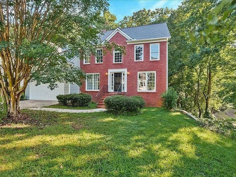 Colonial house featuring a garage, a front lawn, brick siding, and driveway