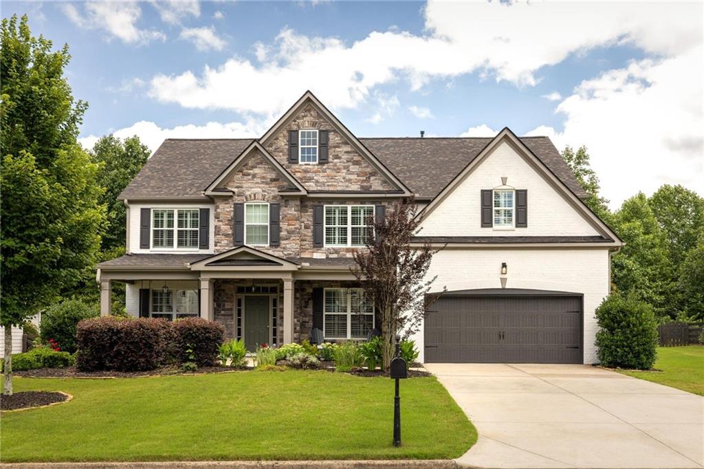 Welcome home to this better-than-new, beautifully maintained brick and stone-front retreat tucked away on a quiet, family-friendly cul-de-sac. With stunning curb appeal and thoughtful design throughout, this home offers the perfect blend of elegance, comfort, and everyday functionality — ideal for modern family living. Step inside to a light-filled, open-concept layout where a wall of windows brings the outdoors in, creating a bright and welcoming atmosphere. Gleaming hardwood floors run throughout the main level, upper hallway, and the serene owner’s suite, providing durability and timeless charm. A private guest bedroom on the main floor features plush carpeting and a full en-suite bath — perfect for visiting family or multi-generational living. The heart of the home is a chef-inspired kitchen boasting crisp white quartz countertops, abundant cabinetry, and high-end appliances — perfect for weeknight dinners or hosting friends for the big game. The kitchen flows effortlessly into the spacious living and dining areas, creating an ideal space for family connection and entertaining alike. Step outside and imagine the possibilities — the fenced backyard is already a great space for play, pets, or weekend relaxation, but the fence line doesn’t yet take full advantage of the generous lot size. There’s ample room to expand, creating your dream outdoor living space, garden, or play area. Location is everything, and this one has it all: just 15 minutes to Avalon in Alpharetta for upscale shopping and dining, and 10 minutes to charming downtown Woodstock — offering the perfect mix of convenience and lifestyle. This move-in-ready gem combines modern finishes, flexible spaces, and a warm, family-focused layout in a truly unbeatable location. Come see why this home checks every box — and make it yours before it’s gone!