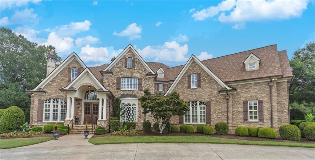 Welcome to this stunning four-sided brick executive estate situated on 7+ private acres featuring a spring-fed, 2-acre stocked pond. This luxurious residence offers elegant architectural details, custom trim throughout, and soaring ceilings designed for both grand entertaining and comfortable everyday living.
The two-story foyer with a curved staircase and iron balusters sets the tone for the home’s craftsmanship. French doors lead to a vaulted library with exposed beams, marble gas fireplace, and built-in bookcases. The main-level owner’s retreat features a sitting area with fireplace, private coffee bar with sink and refrigerator, custom walk-in closet, and a spa-inspired bath with dual shower heads, whirlpool tub, double vanities, and a picture window overlooking the pond.
The heart of the home is the chef’s kitchen, complete with: Wolf 6-burner + griddle & double oven, Sub-Zero refrigerator & stainless appliances including Wine cooler, ice maker, warming drawer & butler’s pantry. Angled butcher block island & breakfast room with wall of windows
Enjoy multiple living spaces including a two-story great room with coffered ceiling, gas fireplace, built-ins, and a wall of windows plus family room off the kitchen with 2 walls of windows, fireplace and bookcases. Formal banquet-sized dining room with columns and heavy trim detail. Biltmore Style back patio with stamped concrete & curved stairs to private backyard
The upper level offers 4 generously sized bedrooms and 3 full baths.
The finished terrace level is an entertainer’s dream, featuring a great room, rec room, theater room, bar with dishwasher & sink, wine cellar, bedroom, full bath, and access to the covered stamped-concrete patio overlooking the pond.
Additional features include: 3-car side-entry garage, laundry room with sink & cabinetry, central vacuum system, whole-house generator, irrigated by designated private well and new roof, circular driveway with ample parking ideal for entertaining.
Convenient to shopping, medical, airport & Battery (home of the Braves)
Experience the perfect blend of privacy, luxury, and serene outdoor living in this breathtaking estate.