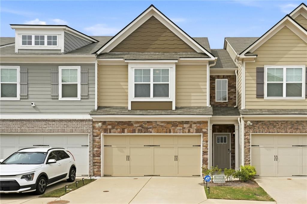 Craftsman-style home featuring concrete driveway, a shingled roof, stone siding, and a garage
