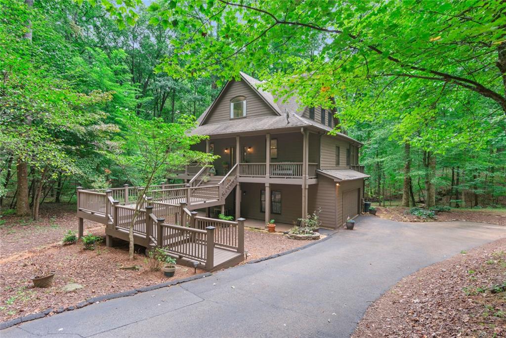 Enjoy the beauty of this elaborate Three Story Custom Built Home in the Heart of the Gated Community of Big Canoe its's the perfect blend of modern comfort and natural charm that offers 3,471 sq ft of tranquil living area with 3 spacious bedrooms, 3 full bathrooms, and 1 half bath, tucked away on 1.6 acres of serenity. Step inside to discover an open concept living area that features genuine hardwood floors, a cozy handcrafted stone fireplace, soaring views from the floor to ceiling windows capturing nature at its finest. The Kitchen is stunning with gorgeous quartz countertops, over 10ft kitchen island, built in wine rack, bar seating, farmhouse sink, new stainless-steel appliances, elegantly crafted cabinets, a breakfast area that makes this the ideal place for Family and Friends. An oversized Primary Suite on the Main, which includes its own private access to a screened in porch, great for enjoying your morning coffee or for unwinding into the evening twilight. Upstairs you'll find a versatile flex space, bedroom with a full bath, a loft overlooking the main level ideal for a home office or a playroom with a cozy reading nook. The lower level boasts as either an in-law suite or a teen retreat, complete with new luxury vinyl plank flooring throughout giving it a modern spin, a separate living area with a coffee bar & wet bar with access to a screened in porch and large patio area. Step outdoors into an oasis, on the large outside deck which is perfect for Hosting all outdoor gatherings and events. Take a walk into your backyard and escape into nature featuring a private creek and beautiful hiking trails to walk and explore. Homeowners also enjoy access to exceptional community amenities, including three lakes for boating, kayaking and fishing a marina, and multiple swimming pools, a wellness center, hiking trails, dog parks, playgrounds, tennis courts, pickleball courts, racquetball along with a championship golf course
Come make this Home Your Own!