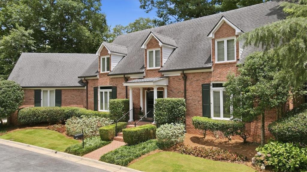 Traditional brick exterior featuring white-framed windows, dark shutters, and multiple dormers