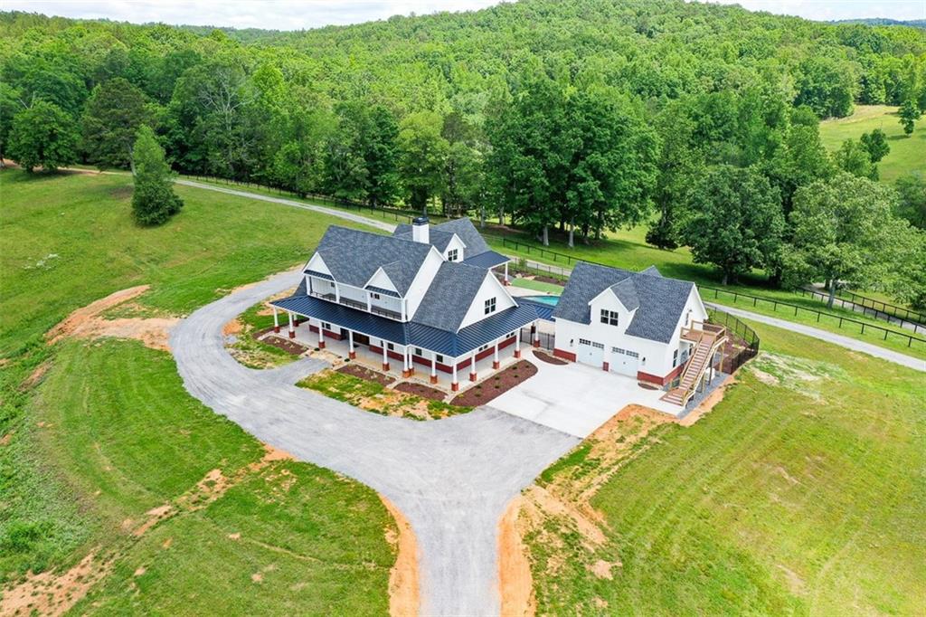 RARE AND IMPRESSIVE NEW CONSTRUCTION FARM HOME WITH POOL, 4-CAR GARAGE, IN-LAW SUITE WITH MULTIPLE POLE BARNS, PASTURES, STORAGE AND A SECOND 5 BEDROOM 5 BATH MODULAR HOME, WITH 2 KITCHENS, PLUS A TINY HOME (CURRENTLY STORAGE) ON 145+/- BEAUTIFUL ACRES ONLY MINUTES TO AMAZING RESTAURANTS AND SHOPPING IN CANTON GA. 1 HOUR TO HARTSFIELD JACKSON AIRPORT, 1.5 HOURS TO CHATTANOOGA TN, 30 MINUTES TO CARTERSVILLE GA AND ABOUT 50 MINUTES TO ELLIJAY GA. MAIN BARN HAS 100x40 UNDER ROOF WITH CONCRETE FLOORS, GARAGE DOORS AND 4 RUNS PLUS 2 FEED ROOMS! THERE'S AN 80x60 PULL-THRU POLE BARN FOR YOUR MOTORHOME, RV'S, TRACTORS AND TOYS -- CONTAINER STORAGE UNIT AND 2-STORY TINY HOME BEING USED FOR STORAGE COULD BE USEABLE WITH SOME MODIFICATIONS. PROPERTY IS ROLLING AND BEAUTIFUL WITH ACCESS ON ADDINGTON, 140 AND SALACOA ROAD. THE NEW CONSTRUCTION HAS BEEN METICULOUSLY PLANNED AND THOUGHTFULLY DESIGNED FOR THE ULTIMATE IN FARM LIFE ENJOYMENT AND RELAXATION. OVERSIZED 2-CAR GARAGE AT KITCHEN SIDE OF HOME HAS BUILT-IN CABINETS AND DRAWERS, PLUS A WASH BASIN SINK AND OPENS TO POOL AREA. GARAGE ENTERS TO FULL-SIZED "PANTRY ROOM" WITH BUILT-IN SHELVES AND CABINETRY. THE MORE THAN AMAZING KITCHEN HAS THE LARGEST CAMBRIA COUNTERTOPS THAT YOU CAN IMAGINE WITH UPGRADED FAUCETS AND LARGE CERAMIC FARMHOUSE SINK. MASSIVE ELECTROLUX BUILT-IN STAINLESS STEEL REFRIGERATOR, MATCHING STAINLESS SHARP MICROWAVE AND ASKO DISHWASHER COMPLIMENT THE PRO-LINE ILLVE 6-BURNER + GRIDDLE GAS STOVE AND OVEN. PROPERTY SERVICED BY TWO 500 GALLON PROPANE TANKS FOR COOKING, POOL HEATER AND BACKUP GENERATOR! THIS HOME IS SURROUNDED BY COVERED PORCHES AND THE AMAZING POOL AREA IS NO EXCEPTION, WITH RELAXING SEATING AREAS UNDER SHADE, WITH WATERFALL FEATURE AND LOUNGING SHELF, ARTIFICIAL TURF SURROUNDS POOL AREA FOR LOW MAINTENANCE. GUEST HOUSE OR IN-LAW SUITE HAS 2 OVERSIZED GARAGES WITH BUILT-IN CABINETS AND OVERLOOKS POOL AREA -- BATH STUBBED BUT SPACE IS UNFINISHED BUT SHEETROCKED -- AMAZING STORAGE OR GAME ROOM, HERE IS A LIST OF THE FEATURES OF THIS PROPERTY WHICH BENEFIT THE NEW OWNERS: 2 feed rooms. Separate run-in shed in one pasture. 2 other sheds. Container for storage with electric. Small storage building with electric. 2 story building with kitchen area that needs a few items to be an apartment. Block building for storage with electric. House with 5 bedrooms and 5 baths and 2 kitchens. Landscaping at house with pool. Trails already cut thru out the property. Roads thru out the property. Very private, there are 26 acers of fenced pasture. Over 1,700 feet of potential commercial road frontage on State Route 140. Over 1320 feet of road frontage on Salacoa Road. Over 210 feet of road frontage on DeBord Drive. Custom Blinds in whole house. Heated towel racks in Master Bath and other downstairs bath. Ceiling fans in all rooms. Master bedroom opens onto pool area. All baths have custom tile. All baths have frameless glass shower enclosures. Walk-in spa tub in master bath. Two master bedroom closets. Custom cabinets thru out the house. TV in master bedroom, master bath, downstairs bedroom, downstairs bath, great room, and office. Cambria Quartz surfaces in kitchen--counters and backsplash. Drawer microwave. Built in freezer and refrigerator. Beverage refrigerator. Ilvie dual fuel range. Large walk-in pantry. Granite top on vanity in powder room. Large mud/laundry room. Office with custom built-in desks and cabinets. Lots of closets. 2 bedrooms with bath each upstairs. Porch upstairs with tile floor. Marvin fiberglass windows and doors. Mahogany grand entry door. Huge finished bonus room. All concrete finished with the Guardian finish--garages, porches, and parking pads Pool with amazing waterfall Hot tub. Cabinets in both garages. Detached garage has apartment fully finished. Washer dryer stack in apt. Separate heat and air in apt. 145+-AC Barn concrete floor--5 garage doors in barn. Run in areas for animals. Auto water for animals in paddocks.