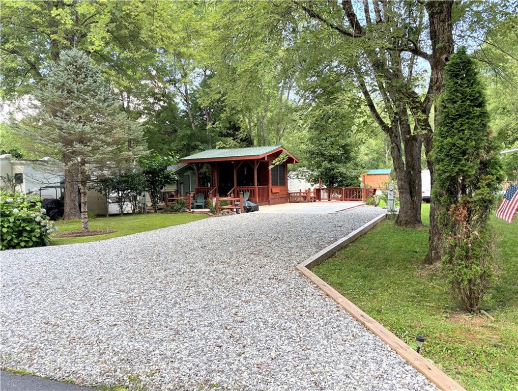 Looking for a little piece of Paradise to enjoy the N. Ga. Mountains, or just to park your RV? Plus, full hook-ups for water, sewer, electric on this level lot with big concrete pad and backs up to green space! Come see this studio style cabin that is stick-built with a 14-foot-long front porch with wicker swing to sit and enjoy the quiet serenity on this Fishtail Circle! It is the perfect sidekick, mancave, or she shed to your RV and has its own Heat/Air! The double wide driveway will fit a larger RV, has a large concrete pad, fresh gravel drive and can still fit 4 plus vehicles! There are nice shade trees surrounding the cabin, a grilling deck with bench seats perfect for entertaining and a Rubbermaid style storage shed including a Honda push mower! Inside are ceramic tile floors, wood walls, and a vaulted wood ceiling with a fan. Furnishings that stay are the daybed couch with under storage, built-in end tables, a corner cabinet plus vaulted storage area. You'll create a lifetime of memories here, whether you're relaxing, fishing, or participating in the ongoing activities within Paradise, a gated community. Enjoy the pool, pavilion, clubhouse, and planned activities! The location is central to all the fun in nearby mountain towns and events, just minutes from Cleveland, Helen, Dahlonega, Clarkesville, and Blairsville. Shop, dine, fish, hike, and visit vineyards-the possibilities are endless! Please note that Paradise is a vacation resort community that does not allow full-time living. The listing agents are owners in Paradise, so feel free to call for a tour or more detailed information about Paradise and this property.
