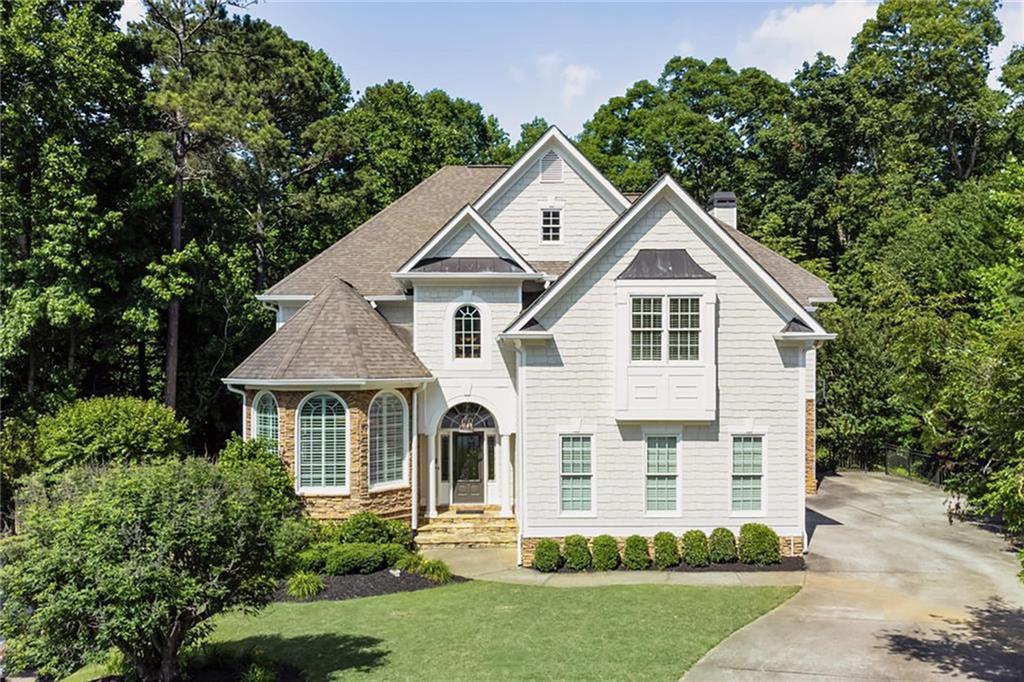 Welcome home to your stunning East Cobb Oasis, situated on a quiet cul de sac. Just a block away from the award-winning Garrison Mill Elementary School you reap the benefits of East Cobb schools while having Roswell in your backyard as well!  You are greeted by a soaring two-story foyer as you arrive flanked by a welcoming front living room opening onto a large dining lined with judges paneling on the walls. The chef’s kitchen offers stainless steel appliances including, 6 burner gas stove and double ovens, and a double basin sink ideally located in the corner overlooking the peaceful backyard. The living room is anchored by the fireplace flanked by built-in cabinetry with ample shelving above. True indoor/outdoor living is just through the door. The oversized back patio overlooks the private backyard and offers both dining and seating options.  The primary bedroom offers a spacious sitting area, a custom closet with wood shelving, and a well-appointed ensuite bathroom with a soaking tub and separate glass-enclosed shower opposite the dual vanity. Each of the secondary bedrooms are filled with natural light and offer ensuite bathrooms with upgraded finishes. The large laundry room features ample cabinetry with a laundry sink. Don’t miss the additional bonus room with custom built ins for desks and making for the perfect secondary living room or home office upstairs.  
The large daylight terrace level flows out onto the built in grilling area and private Astro turf yard accented by an additional seating area and built in firepit, not to mention a built-in grilling station. The terrace level continues the entertainers dream with a custom wet bar, movie room as well as ample entertaining space, built in window seats for additional storage and a room which could serve as a home office, gym or guest room. Located in Marietta, just minutes from Historic Roswell, top schools, restaurants, and shopping. Enjoy swim and tennis amenities at the Highlands of Wesley Chapel not to mention Mabry Park just down the road complete with playgrounds, walking paths, pond and meadows. Photos 4, 25, and 30 are virtually updated to show the Primary Suite and Primary Bathroom in a Neutral Color.