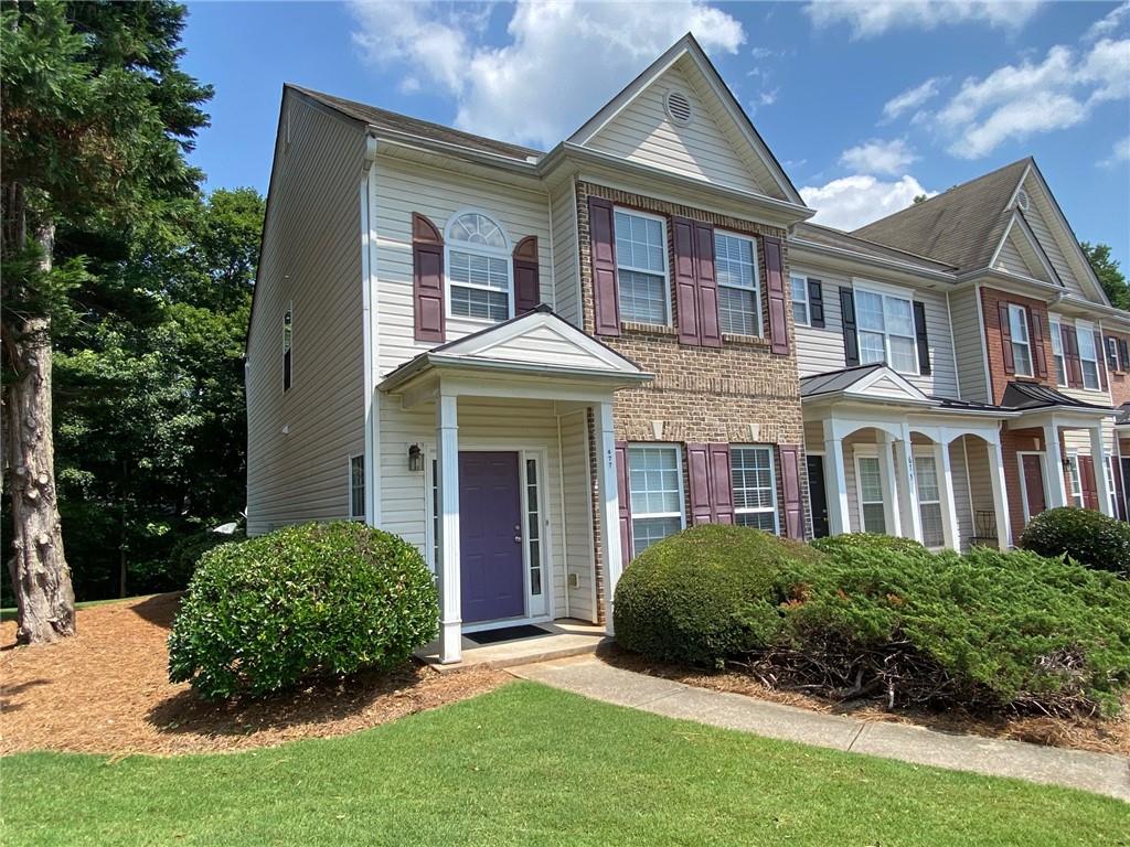 Two-story townhome featuring a brick and siding facade with accent shutters