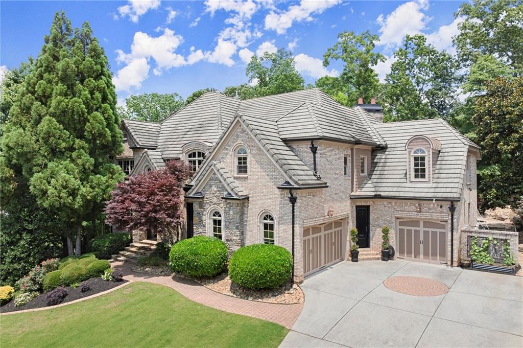 Create unforgettable memories in this extraordinary East Cobb estate, tucked away on a quiet cul-de-sac in the top-ranked Lassiter High School district. You’ll first notice the impressive curb appeal with mature landscaping, a stately brick and stone exterior, and a 3-car garage. Enter through the double wrought iron doors into the soaring two-story foyer, where rich cherry hardwoods, exquisite craftsmanship, and warm architectural details welcome you home. Host up to 12 guests comfortably in the formal dining room. Relax in the stunning great room, where coffered ceilings, floor-to-ceiling windows, and a fireplace flanked by custom built-ins create a cozy yet sophisticated ambiance throughout the home. Gather in the chef’s kitchen, designed for both everyday living and grand entertaining, outfitted with Subzero and Wolf appliances, custom wood cabinetry, a hidden walk-in pantry, and a spacious island that flows seamlessly into the vaulted keeping room, complete with a stacked stone fireplace. A guest suite on the main with an ensuite bath is ideal for multigenerational living or long-term visitors. Retreat to the freshly painted upstairs primary suite, featuring a sitting area with a gas fireplace, two custom walk-in closets, and a spa-inspired bath with dual vanities, granite countertops, a large walk-in shower with bench seating and dual showerheads, and an oversized jetted soaking tub. Work from home in the dedicated office space off the bedroom. There is plenty of space in one of the three generously sized secondary bedrooms, each with its own
ensuite bath and custom walk-in closet. The terrace level is perfect for entertaining and offers flexible spaces ideal for your favorite game table, working out, or staying in for movie night. The custom bar is fully outfitted with two dishwashers, a beverage cooler, a pull-out drawer, an ice maker, and a sink, making hosting a breeze. A full bathroom, in addition to a half bath, adds flexibility, making this level ideal for providing guests with a private bedroom suite. Escape to your private backyard oasis, featuring lush landscaping, a heated PebbleTec saltwater pool with a waterfall, jacuzzi, an updated filtration system, and a terraced playground. You'll love the seamless flow as you grill in the covered outdoor kitchen and gather around the custom stone firepit. Additional upgrades include one new AC unit with a lifetime warranty, two new water heaters, whole-house surge protection, Nest thermostats, a new Ring security system, and irrigation and outdoor lighting sensor systems. This one-of-a-kind property is designed to impress and built to entertain. Don’t miss your rare opportunity to own your dream home in one of East Cobb’s premier locations, with convenient access to downtown Roswell, historic Marietta, I-75, and just minutes from restaurants and shopping.