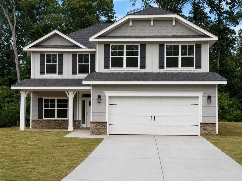 Two-story residence featuring light gray siding with dark shutters, a front porch with white columns, and stone accents