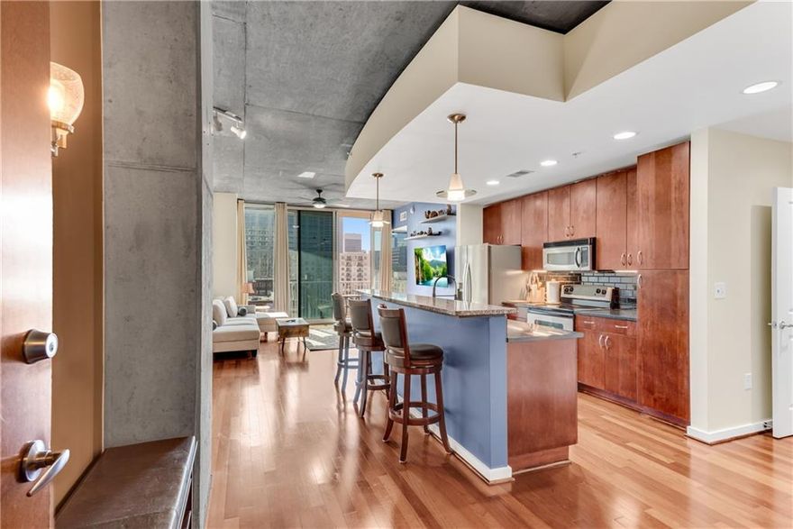 Sunny unobstructed southern views of Downtown!  Largest 1 Bedroom plan at Spire!  Hardwood floors throughout and 10' exposed concrete ceilings.  This popular plan features a huge island kitchen larger than in some of the 2 bedroom plans!  The kitchen has an area for a bistro table or small dining table as well as a built-in desk area, drop zone or bar area. WASHER/DRYER/FRIDGE all included.  Living area w/access to the covered balcony.  The ONLY 1 bedroom plan in Spire that features a full wall to the bedroom as well as his & her closets!  Spacious bathroom has an oversized vanity and linen closet.  Large laundry area that is NOT stack units! One deeded covered parking spot in the gated parking garage. Spire features 24 hour concierge, club room, swimming pool, grilling area & fitness center. Walkable to restaurants, Fox Theater, GT, Piedmont Park and more!