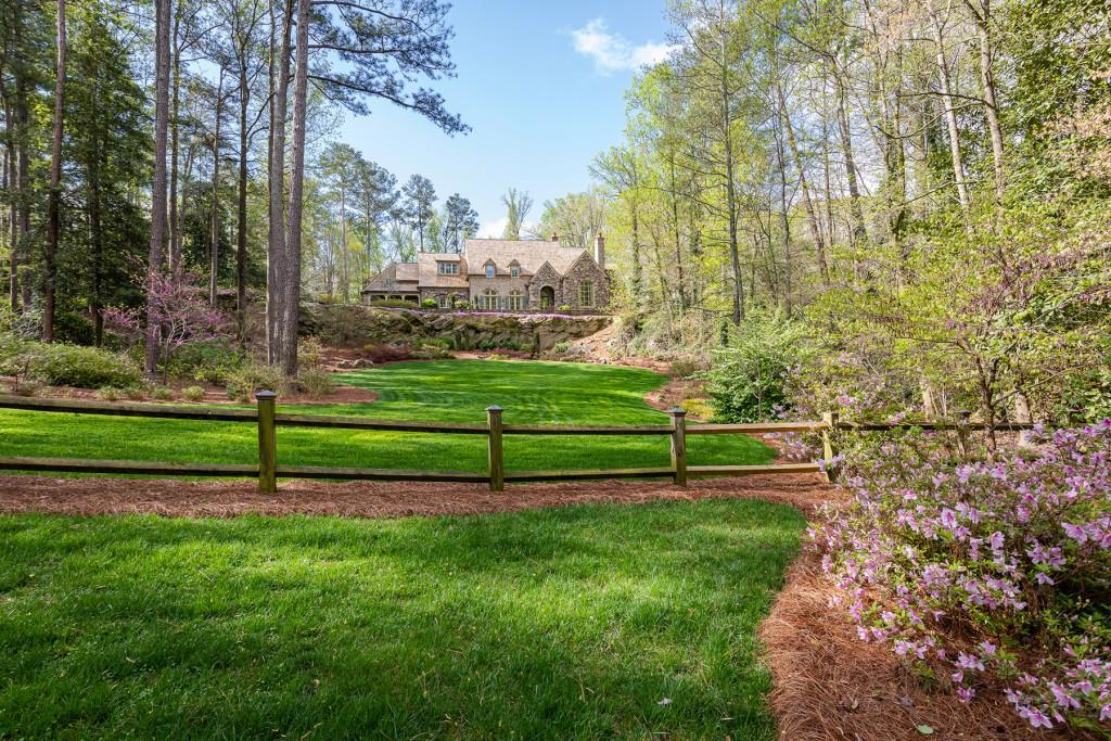 "Quarry Crest," a one-of-a-kind, iconic, gated estate home, sited on a 2.5-acre private hilltop. Built in 2005 by renowned Atlanta builder Bob Goodsell, every detail exudes quality. With updated finishes and appliances added in 2020, this enchanting home is move-in ready.Soaring 12-14 foot ceilings throughout the first floor allow natural light to fill each room of this masterfully designed home. A barrel-vaulted ceiling connects the banquet-sized dining room to the gourmet cook's kitchen and two-story family room where a fireplace prefaces the stunning views of the walkout level yard, heated saltwater pool, tranquil waterfall and inviting loggia. French doors easily open to the breezeway for the full-size server's bar. The main level also features a formal living room as well as a spacious private guest suite and a handsome wood-paneled study - all overlooking the expansive front lawn.A grand staircase ascends to the second level, which hosts the tranquil primary suite. Truly a relaxing haven, this retreat impresses with a bathroom offering separate vanities, huge closets and a morning bar. Three additional, spacious, second-level bedroom suites are served by a large and convenient second laundry room.A playground for all, the terrace level boasts a theater, a 1,000-bottle wine cellar, a professional-size gym with a dry sauna and a guest room or massage room - all served by a full bathroom. The fabulous entertaining areas continue outside to the pool cabana's outdoor fireplace, integrated TV and adjacent grilling area. A Jacuzzi spa overlooks the peaceful waterfall.Additional amenities include a second staircase, a first-level laundry room , a cedar shake roof, a three-car garage and an abundance of room for guest parking.