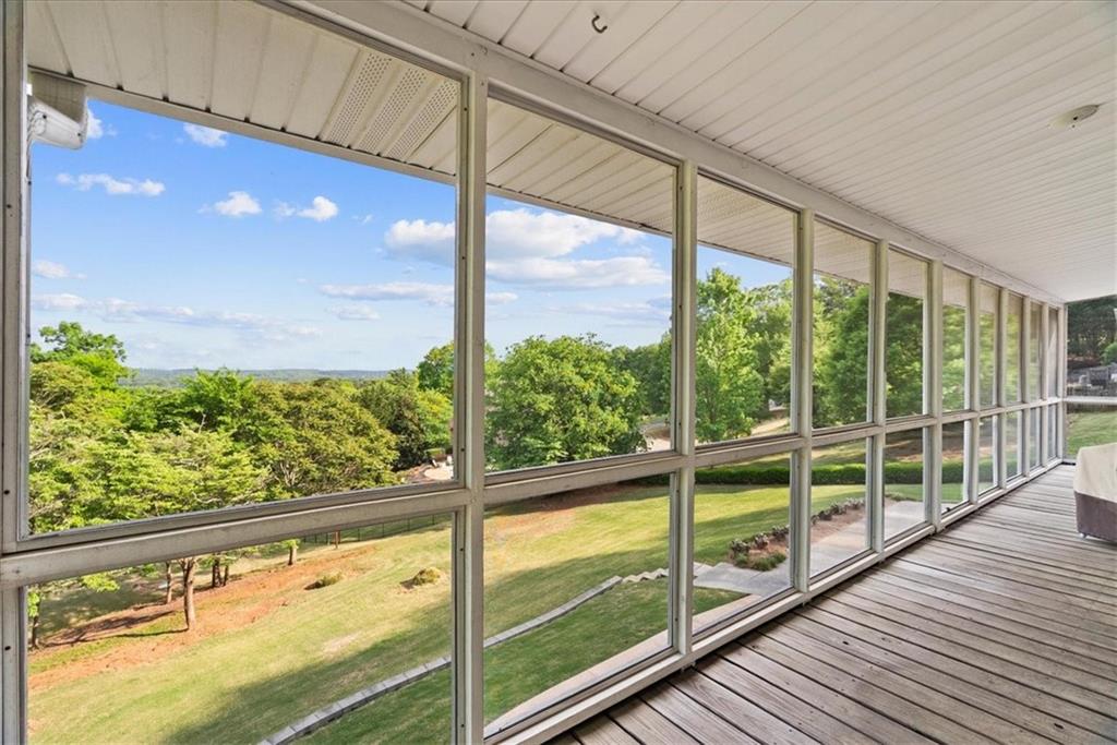Expansive enclosed porch with wood-finish flooring and a white paneled ceiling