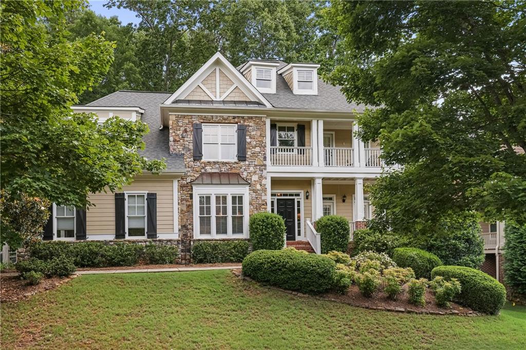 Welcome to 4874 Registry Lane, a beautifully maintained home with stone and siding exterior and charming double front porches, nestled in the sought-after Burnt Hickory Registry—an established swim, tennis, and playground community served by top-rated schools. The main level offers a formal living room, dining room, and a spacious great room featuring built-ins and a cozy fireplace, open to the kitchen and breakfast area. A private guest bedroom and full bath are also located on the main floor. Step out from the kitchen to a quiet patio and enjoy the lush, green backyard—ideal for outdoor dining or relaxing. Upstairs, the restful primary suite includes a sitting room, access to a private upper porch, and a well-appointed bathroom with dual vanities, a separate tub and shower, and a walk-in closet. Three additional bedrooms and two bathrooms complete the upper level. The finished terrace level provides a large living area, bar, full bathroom, and three unfinished spaces for added storage or future expansion. This home offers the perfect blend of comfort, function, and location in one of Kennesaw’s most desirable neighborhoods.