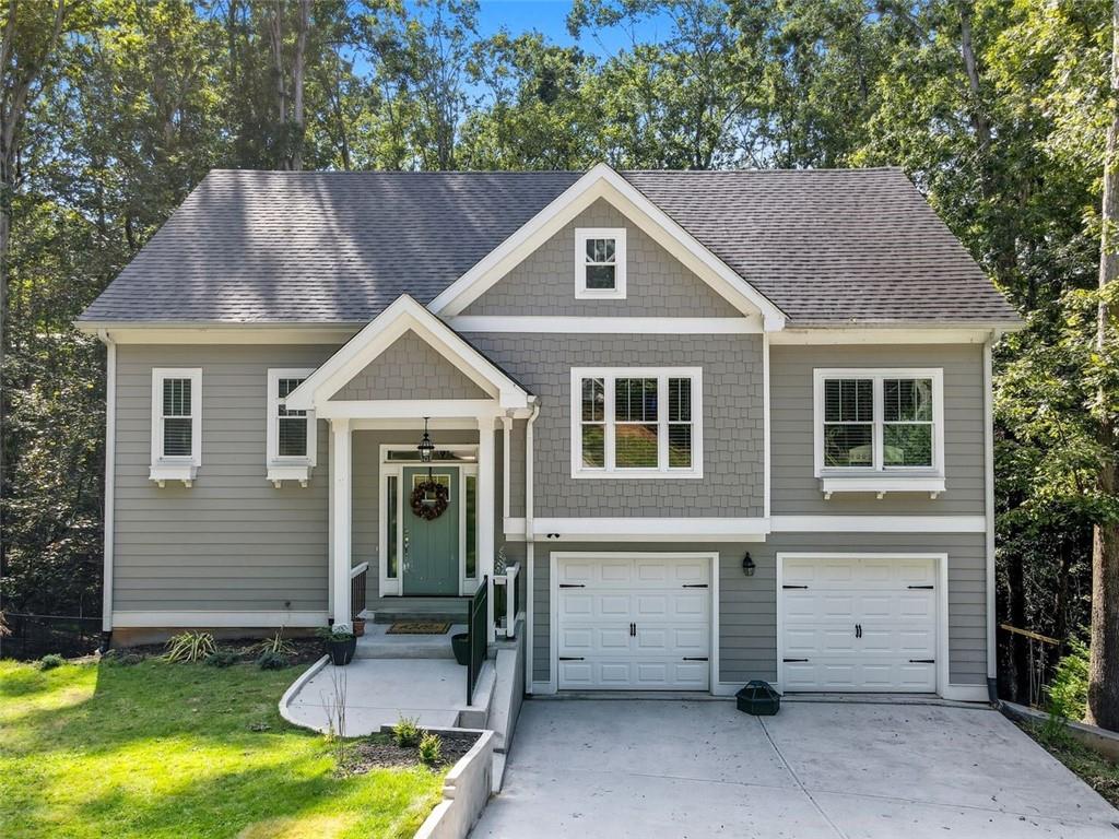 This charming split-level home is nestled in an established Lake Lanier neighborhood and offers a welcoming open floor plan with LVP flooring and a cozy wood-burning fireplace in the great room. The kitchen features white cabinetry, stainless steel appliances, and a warm, inviting atmosphere, all overlooking peaceful wooded views from the back of the home and deck. The primary suite and bath is conveniently located on the main level and includes granite countertops with dual vanities, white cabinets, a separate garden tub and shower, beautiful tile flooring, and a spacious walk-in closet. Two additional bedrooms and a full bath are also located on the main level, along with a laundry room for added convenience. The finished lower level provides two more bedrooms, one with its own private deck. This lower level space that can easily function as an office, guest room, or additional family room. A Jack-and-Jill bathroom with white cabinets and tile flooring adds both charm and practicality to this level. The home sits on a private, fenced wooded lot and is ideally located near shopping, restaurants, Simpson Park, Robinson Park, and multiple boat ramps. A large staircase in the garage leads to an unfinished basement with exterior access, perfect for storage or future expansion. With durable hardy board siding and thoughtful design throughout, this home blends comfort, functionality, and natural beauty in one exceptional package.