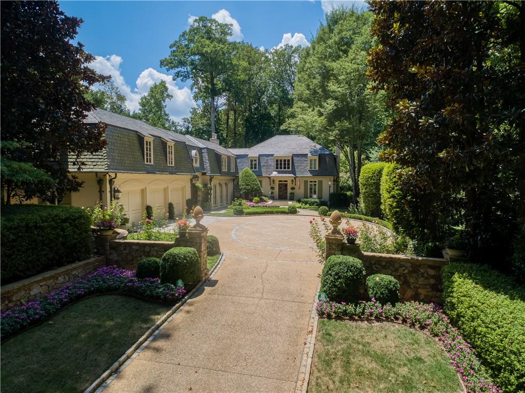 Tucked away on an impeccably landscaped and private half-acre lot, this stunning European-style residence blends classic 1947 craftsmanship with the sophistication and comfort of modern living. With its painted brick facade, slate roof, and mature gardens, this home radiates enduring elegance in one of Buckhead’s most convenient locations.
A two-story limestone foyer welcomes you inside, setting the tone for the home’s refined character. To the right, a cozy office/study offers custom built-ins, a charming bay window, and its own powder room.
Step down into a lovely fireside living room with custom moldings, floor-to-ceiling built-ins, and another bay window. The dining room with hidden storage and French doors opens onto a brick patio surrounded by lush gardens.
At the heart of the home lies a bright, cheerful kitchen with breakfast bar, and breakfast area opening into a fireside keeping room with vaulted, beamed ceilings, custom cabinetry, and access to the private backyard. A spacious, additional family room is adjacent to the kitchen.
The private primary suite features a custom-designed walk-in closet and a lovely bathroom with dual onyx vanities, a soaking tub, and separate glass shower. Five additional bedrooms and three full baths provide flexibility for family, guests along with a dedicated office featuring built-in desks. The upstairs laundry room with utility sink and cabinetry completes the upstairs level.
The finished terrace level features a handsome oak-paneled recreation room with beamed ceiling, wet bar, built-in bookshelves, and a powder room. There are 2 separate wine storage rooms.
The grounds are beautifully landscaped surrounding the brick patios and fountains - all part of the charm of this special property.
Welcome HOME!
