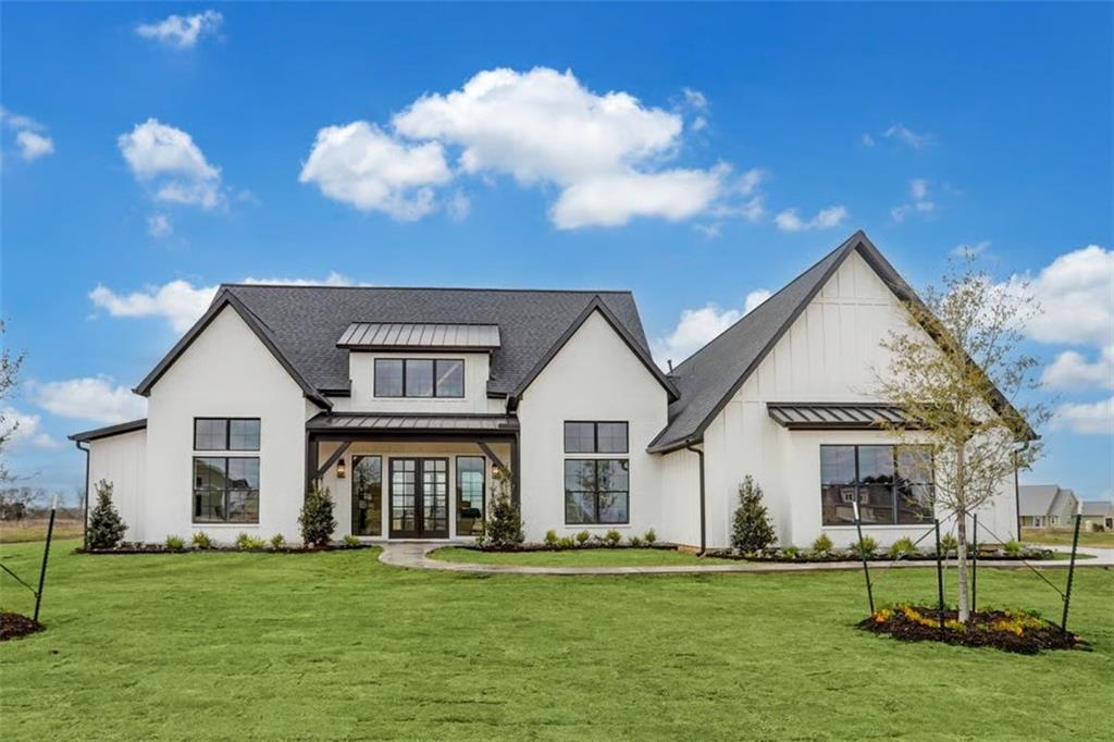 Transitional Farmhouse Elegance with Indoor-Outdoor Harmony
Experience seamless living in this beautifully designed 4-bedroom transitional farmhouse, where French doors at the front and rear invite natural light and create effortless flow between indoor and outdoor spaces.
The symmetrical exterior, defined by a broad central shed dormer and flanking gables, delivers timeless curb appeal. Step inside to a vaulted great room anchored by a statement fireplace, while the open-concept kitchen impresses with a large island, wraparound seating, and a sunlit walk-in pantry.
The private primary suite is a true retreat, featuring a spa-like ensuite and direct access to the laundry room for ultimate convenience. Three additional bedrooms are thoughtfully arranged on the opposite wing, with a Jack-and-Jill bath serving two.
A side-entry double garage leads into a well-appointed mudroom with built-in lockers—perfect for organizing your daily essentials.
**Luxury Highlights:**
* Vaulted great room with fireplace
* Expansive walk-in pantry with natural light
* Front and rear French doors for light-filled living
* Spa-inspired primary suite with laundry access
* Side-entry garage with mudroom built-ins
* Optional finished bonus space available
8 month built time from contract