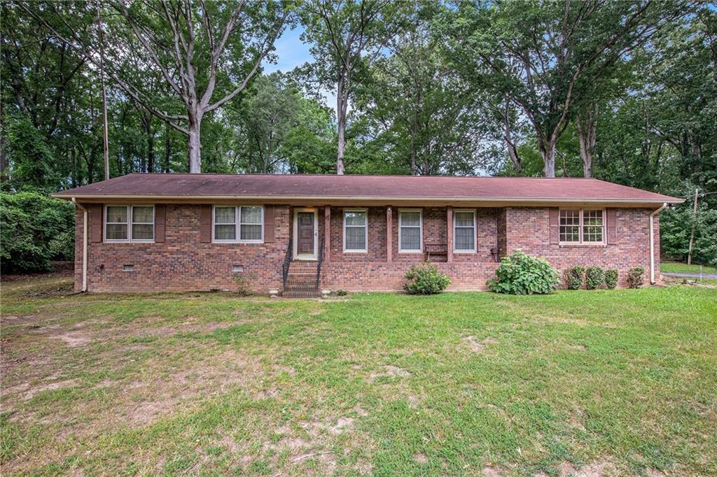 Discover the potential of this classic 4-sided brick ranch home, peacefully situated on 2.31 acres of picturesque land. This 3-bedroom, 2-bath residence offers a solid foundation with timeless construction and is ideal for those seeking to customize a home to their own tastes. The inviting family room features a traditional brick fireplace, providing a warm and welcoming focal point and is open to the cute eat in kitchen. The front of the house has a more formal living room and dining room combination with large windows. A spacious screened-in porch overlooks the expansive and private backyard, offering the perfect space for outdoor enjoyment in any season. Additional features include a 2-car carport and a private well, adding both convenience and value. With a bit of updating and care, this property presents an excellent opportunity to create a beautiful home in a tranquil setting.