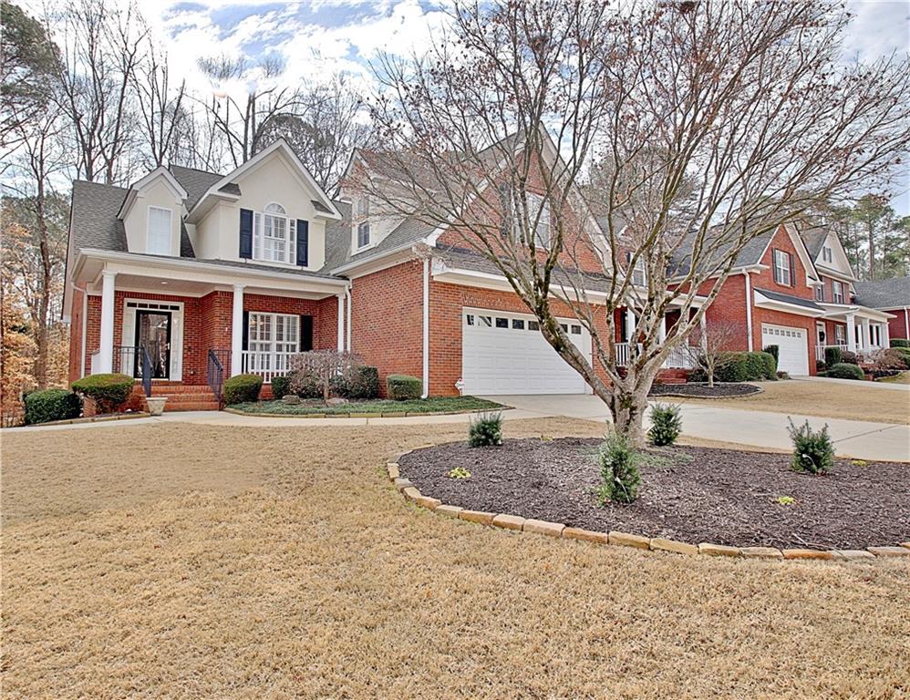 Traditional-style home featuring covered porch, driveway, brick siding, and a garage