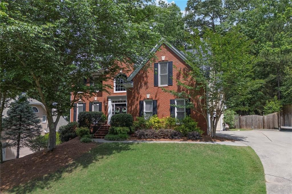 SELLER OFFERING A RATE BUYDOWN! Seller is offering a rate buydown that could lower your interest rate by 1% and therefore your monthly payment by $350-$400/month (varies based on amount financed). Great opportunity to make this beautiful Towne Lake home yours with a lower monthly payment. This home located in Wellesley Subdivision home combines classic charm with modern convenience and features a brick-front with a side-entry garage, 5-bedrooms, 3.5-bathrooms. Step inside to find gleaming hardwood floors throughout the main level. A formal living room (or flexible space) flows seamlessly into the elegant dining room, perfect for entertaining. The open-concept kitchen is a chef’s dream—complete with a center island, granite countertops, stainless steel appliances, double ovens, and a view to the expansive family room. Cozy up by the striking floor-to-ceiling stacked stone fireplace, a true centerpiece of the home. Upstairs, you'll find hardwood floors in the hallway and all four bedrooms, including an oversized primary suite and a secondary bedroom that is oversized with high ceilings and a walk-in closet. The finished basement features a fifth bedroom (or home office), a full bathroom, a large open area with a wet bar, and a second washer/dryer hookup. A spacious workshop or unfinished storage area adds even more value and functionality.
Step outside to your private backyard oasis. Relax on the upper deck, soak in the sunken hot tub, or gather around the fire pit. The lush landscaping, mature trees, blooming shrubs, and full privacy fence create the feel of your own private park. A lower patio and a level play area—ideal for a trampoline or play set—complete this serene outdoor space. Wellesley offers top-notch amenities including a pool with slide, tennis and pickle ball courts, a shaded playground, and a spacious clubhouse. Conveniently located near shopping, dining, and easy interstate access, and top notch schools!