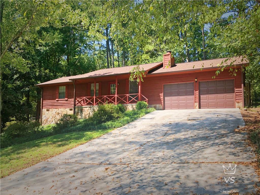 Exterior featuring red horizontal siding, a stone foundation, a covered front porch with a red railing, a brown shingle roof, and a two-car attached garage with brown doors
