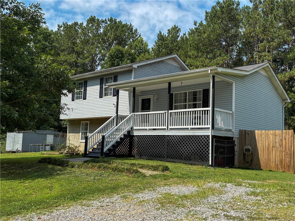 Split-level home featuring light blue siding with black window shutters and a covered porch