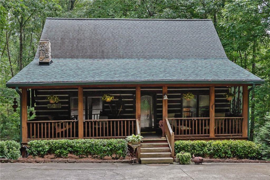 Escape to your own private retreat just minutes from Downtown Woodstock and Roswell! Set on two serene acres with beautiful oak hardwoods, this stunning hewn log cabin home offers the perfect blend of rustic charm and modern comfort. Tucked away from the road for ultimate privacy, you’ll feel like you’re in the mountains while still being close to shopping, dining, and all that Woodstock and Roswell have to offer. The welcoming front porch is ideal for morning coffee, while the enclosed screened/glass back porch provides year-round enjoyment with peaceful backyard views. The fenced front yard is perfect for pets, and the soothing sound of birdsong completes the tranquil setting. Inside, the main level features hardwood floors under the carpet and a charming wood-burning fireplace that can heat the entire home in the winter, plus a propane gas backup heat system for peace of mind. The unfinished basement spans the full length and width of the home, is stubbed for a bathroom, and is ready to be transformed into anything your lifestyle requires. Enjoy energy efficiency year-round thanks to the natural insulation of log construction. This solidly built home is designed to stand strong against whatever Mother Nature brings. If you’ve been dreaming of a private log cabin lifestyle with modern convenience close by, this is your chance. Schedule your visit today—this one is full of charm and won’t last long!