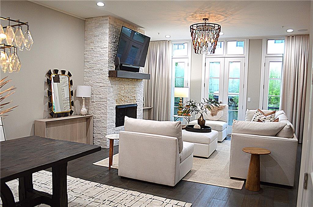 Experience the charm of Historic Brookhaven in this beautiful, light-filled townhome featuring an ELEVATOR to all floors. Nestled within the sought-after Aldredge development, this meticulously designed home prioritizes privacy and offers a wonderful open floor plan with 10-foot ceilings throughout.
The impressive 4th floor Entertaining Den, showcased on the cover of Interiors Atlanta magazine, seamlessly connects to the expansive covered rooftop terrace, complete with a built-in fireplace for cozy gatherings. The living room boasts a wall of windows adorned with custom treatments, complemented by a striking brick accent wall in the foyer.The elegant kitchen is equipped with high-end appliances, an oversized island, and a built-in wine room that’s easily accessible. Enjoy peaceful views from the kitchen-level grilling porch and keeping room, overlooking the serene trees at the back of the community. The spacious primary bedroom is flooded with natural light and features a luxurious bathroom with double vanities, an oversized walk-in shower, an extra-large closet, and a separate shoe closet! Each secondary bedroom is generously sized, ensuring privacy for guests or family. The terrace-level bedroom with an en-suite bath boasts delightful access to the charming brick patio. Thoughtful touches like custom blinds, window treatments, and designer lighting enhance both functionality and elegance with the televisions and media included in the sale. Ideally located within walking distance to the Capital City Club, shopping, and restaurants, this gated community perfectly blends luxury, prime location, and a vibrant lifestyle.