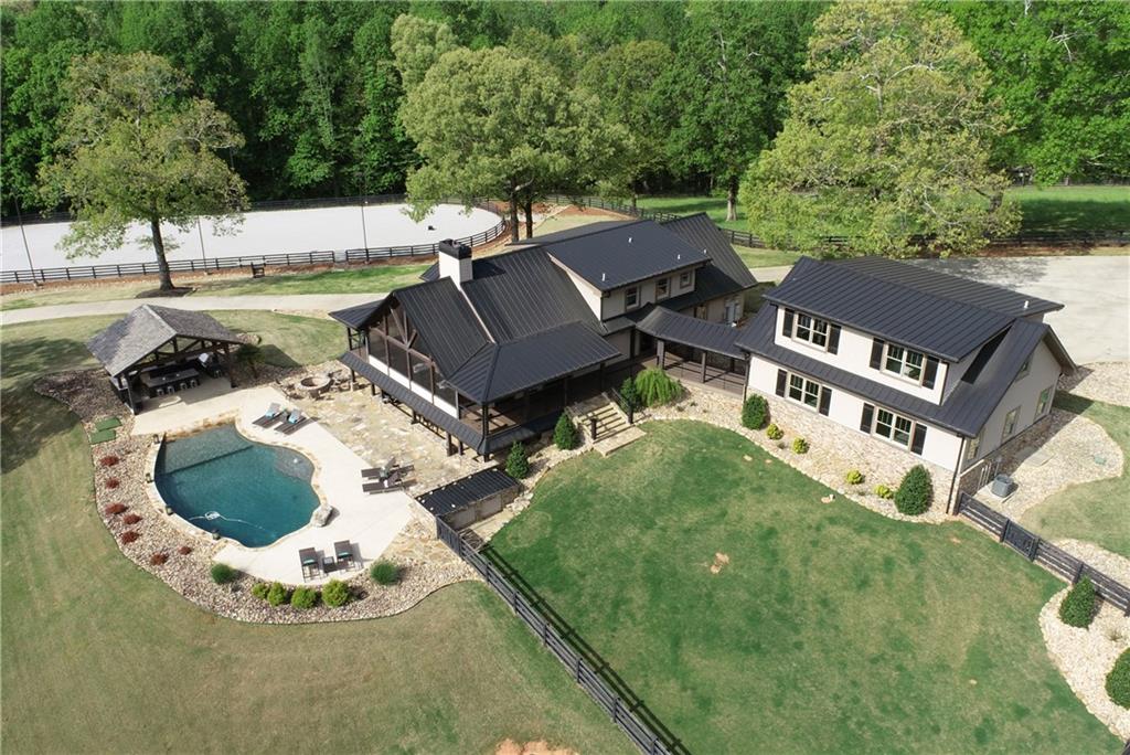 Regal Farms is truly a “One Of a Kind” Premier Luxury Estate. As you enter through the 1st of two private gates, you will feel magically transported coming upon a sensational reveal of this Western Lodge inspired home, designed to showcase the natural beauty of the property w/expansive views & high-end design elements creating a luxurious organic feeling for all the senses. Situated on almost 30 acres, it encompasses a main residence w/pool, high-end horse facilities, arena, barndominium, multiple outbuildings, pond and 7 rolling pastures. Design style is cohesive & consistent across the entire estate. The residence features 4 bedrooms, 3.5 baths where the main level perfectly complements today’s modern lifestyle w/an open concept where formal & informal spaces flow into each other. Showcased by vaulted ceilings w/barnwood beams, floor to ceiling stone FP and two sets of French doors open to covered porch, exemplify this lifestyle. Solidly built w/attention to detail such as Paradiso natural oil finished wood floors throughout. Chef’s kitchen includes a DCS 5 burner commercial range w/griddle & convection oven, built-in Thermador refrigerator/freezer, microwave drawer & expansive counterspace. Rustic finished cabinets, metallic backsplash & black leathered granite pair richly w/the modern Stainless Steel pieces. Owner's suite retreat to relax w/barnwood coffered ceiling & accent wall, natural stone tiled oversized dual shower w/rain head & body spray jets w/heated floors, custom reclaimed wood double vanities and matching medicine cabinet. Upstairs are two oversized bedrooms w/private bath. Terrace level has home gym, in-law suite and full bath and rustic glam themed mutli-purpose space w/tongue & groove ceilings, FP and bar area perfect for movie premieres. French doors open to al fresco dining on the patio poolside across from covered outdoor kitchen. Heated saltwater pool wiPebble-tec finish, beach entry w/2 sunbathing ledges and diving rock. Every level of the home is designed to allow for a seamless indoor-outdoor experience. Above 2 Car Garage is 1 bed/1bath apartment w/full kitchen & living room. Could be a fantastic artist's studio w/tons of natural light. Designed for the horse lover, is the 6-stall barn w/extra wide concrete center aisle, hot/cold wash stall, spacious caretaker's apartment above, round working pen, lighted 75 x 180 arena w/sand & water and 7 rolling pastures w/four-board fencing. Custom Chicken Coop, and separate Barn for the Goats & Donkeys. Barndominium has 4,800 sq ft fin. space, w/13 Big screen TVs, indoor stage area, PA & sound system, fiber internet. With 3 bathrooms, incl. handicapped accessible & 4 sep. bathroom stalls, this area can easily handle up to 100 guests. Bunkhouse area has a full kitchen, living, full bath & laundry w/ 4 bunk beds, sleeper sofa & FP. Out back are 3 more TVs, full outdoor kitchen & hot tub! Fully functional commercial kitchen in the barndominium, with 4 beer taps, keg cooler & refrigerator, bar sink prep location & drink serving area, can handle it all. Side parking allows for multiple Food Trucks if you prefer to cater. From swimming, basketball, fishing, volleyball, horseback riding to playing inside a game of pool or shuffleboard, fun for all. There are 6 stall areas in the barndominium perfect for car collections. Entire floor has built-in drains & granite floor finish. Ample power to run mechanics tools & compressed air outlets available in all stall areas. Behind the main barn is an oversized 1,500 sq ft, 2 car finished garage w/large concrete pad. Another 2,500 sq ft equip. storage barn w/concrete floor, oversize garage doors for storing farm equipment. With two separate addresses attached to the estate, creating a commercial space or directing guests to a party is easy. Regal Farms is perfect as a hobby farm, corporate retreat center, event venue or simply a stunning private getaway - Endless Possibilities!