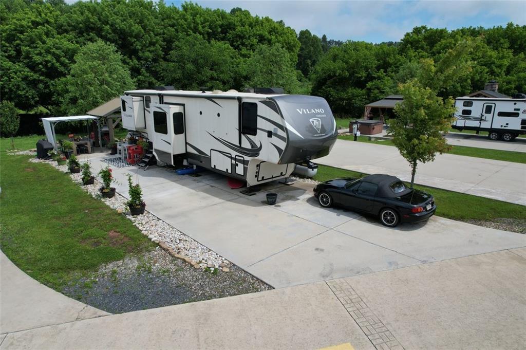 If you're dreaming of a peaceful spot by the water, this creekside RV lot might be just what you’ve been waiting for. Tucked along the banks of Hemptown Creek, it’s a place where you can unwind, sip your coffee by the fire, fish on your property, and listen to the soothing sound of water flowing just steps away. The lot is beautifully landscaped and set up for outdoor enjoyment. There’s a 21'x75' concrete pad that easily fits larger RVs or a tiny home, plus a gazebo with a fireplace—perfect for cool evenings or cozy conversations. A pergola extends the shaded outdoor space and invites you to enjoy meals outside, surrounded by the fresh mountain air. Closer to the creek, a fire pit seating area gives you a front-row seat to nature’s soundtrack. Across the creek, a peaceful open pasture adds to the serene view. Whether you’re looking to relax or entertain, the layout is functional, welcoming, and full of charm. Located in the gated Waterside at Blue Ridge community, you’ll also enjoy amenities like a pool, clubhouse, playground, dog park, pickleball, disc golf, and more—all just minutes from downtown Blue Ridge and outdoor adventures galore. The area offers a lot of activities during all seasons - from tubing, boating, fishing, hiking, waterfall chasing to wine tasting, apple picking, train trips to the state line. Close to Lake Blue Ridge, Toccoa River, Toccoa Swinging Bridge, Aska Adventure area, Lake Nottely, multiple parks, Downtown Blue Ridge. This one’s not just a lot—it’s a mood.