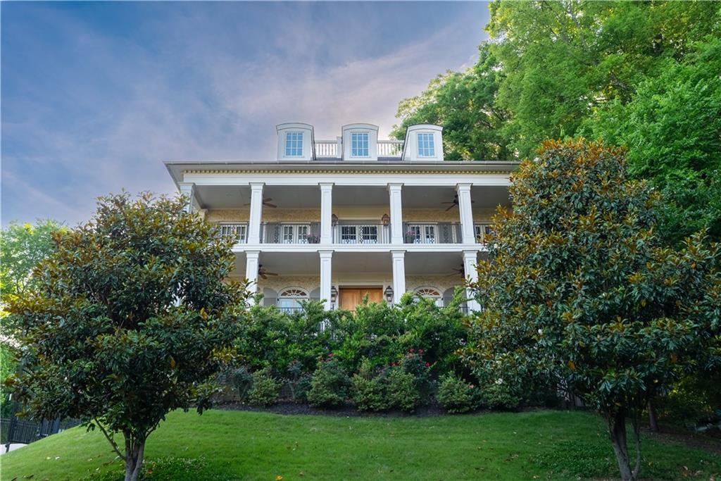 Welcome to an icon of Midtown—where modern-antebellum elegance and resort-style amenities meet on the largest residential lot in the Garden District. Tucked quietly away from the street, yet instantly recognizable from the BeltLine, this residence commands attention with its double-height verandas, elevated site, and a one-of-a-kind widow’s walk offering sweeping 360° skyline views and sunsets you won’t forget.
Completed in 2017 and thoughtfully expanded since, the home unfolds across 6,898 finished square feet on four levels, delivering eight bedrooms and seven and a half baths. The classic facade is lined with eight sets of French doors, flooding the main floor with light and opening directly onto the verandas. Ten-foot ceilings crown the main level, which also boasts its own laundry for added convenience.
Step outside to a heated salt-water pool, perfectly positioned for privacy and effortless entertaining, with two additional sets of French doors leading to the backyard oasis.
The vaulted owner’s retreat is a world unto itself—enjoy serene pool views, direct access to the veranda, a separate sitting room with a mini wet bar, and a private connection to an adjoining bedroom ideal for a nursery or home office.
On the third floor, another laundry room—complete with a sink and generous folding space—makes everyday living seamless. The fourth level offers two spacious bedrooms, abundant attic storage, a Jack-and-Jill bath, and access to the rooftop deck, where the city unfolds in every direction.
Downstairs, host guests in a private suite, stay active in the professional gym, unwind in the steam shower, and rest easy with a concrete-encased panic room. The three-car garage is EV-ready for modern convenience.
Estate-scale grounds blend with Midtown’s walkability: stroll three minutes to the Eastside BeltLine Trail, Home Depot, Whole Foods, Trader Joe’s, and Ponce City Market; Piedmont Park is just a ten-minute walk away.
This is more than a home—it’s Midtown’s landmark estate, offering rare land, unforgettable views, and the kind of privacy and access that’s only possible here.