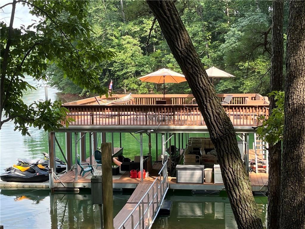 A VERY RARE FIND ON LAKE LANIER - This one of a kind lake front property features your own large private cove in Very Deep Water, isolated from the wind and in a no wake zone. No other dock can be permitted in the cove, so you will be able to enjoy complete privacy and peace. Come enjoy the most beautiful sunsets from your double slip dock with party deck that also comes with a permit to drive down to the lake. This house comes with two lots, just shy of an acre. The second lot is all grass and ready for any new addition to the house or leave as it is & have a great level play area. This Gorgeous ranch style home provides a full length porch on the front of the home & views of the Lake from both levels of the back of the home. It has been completely renovated with exposed beams, hardwoods throughout, phenomenal kitchen, bathrooms & finished daylight terrace level including your own bar. The Desirable Open Concept provides access to the screened porch and large deck on the main level allowing you additional space to entertain and enjoy the view & the finished daylight terrace level provides a large family/rec. room with custom bar, office, bedroom, full bath & exterior entrance which leads to the large covered patio, fire pit, lake & driveway areas. The detached garage was recently closed in and offers two parking spaces, one high enough to store a boat and two workshop/storage areas with garage door access to park a golf cart or ATV. Six additional parking spaces available on the parking pad next to the garage. If you enjoy entertaining this is a Must See! Located by the Six Mile Bridge, super close to GA 400, Publix & more! Call today to schedule your appointment to preview.